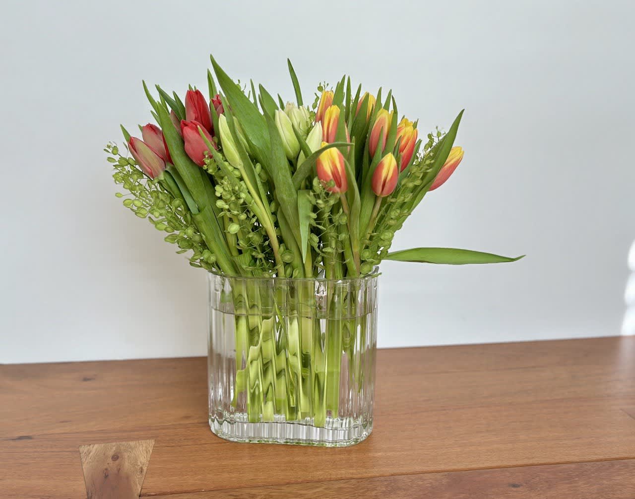 Bouquet of red, yellow, and white tulips in a clear glass vase
