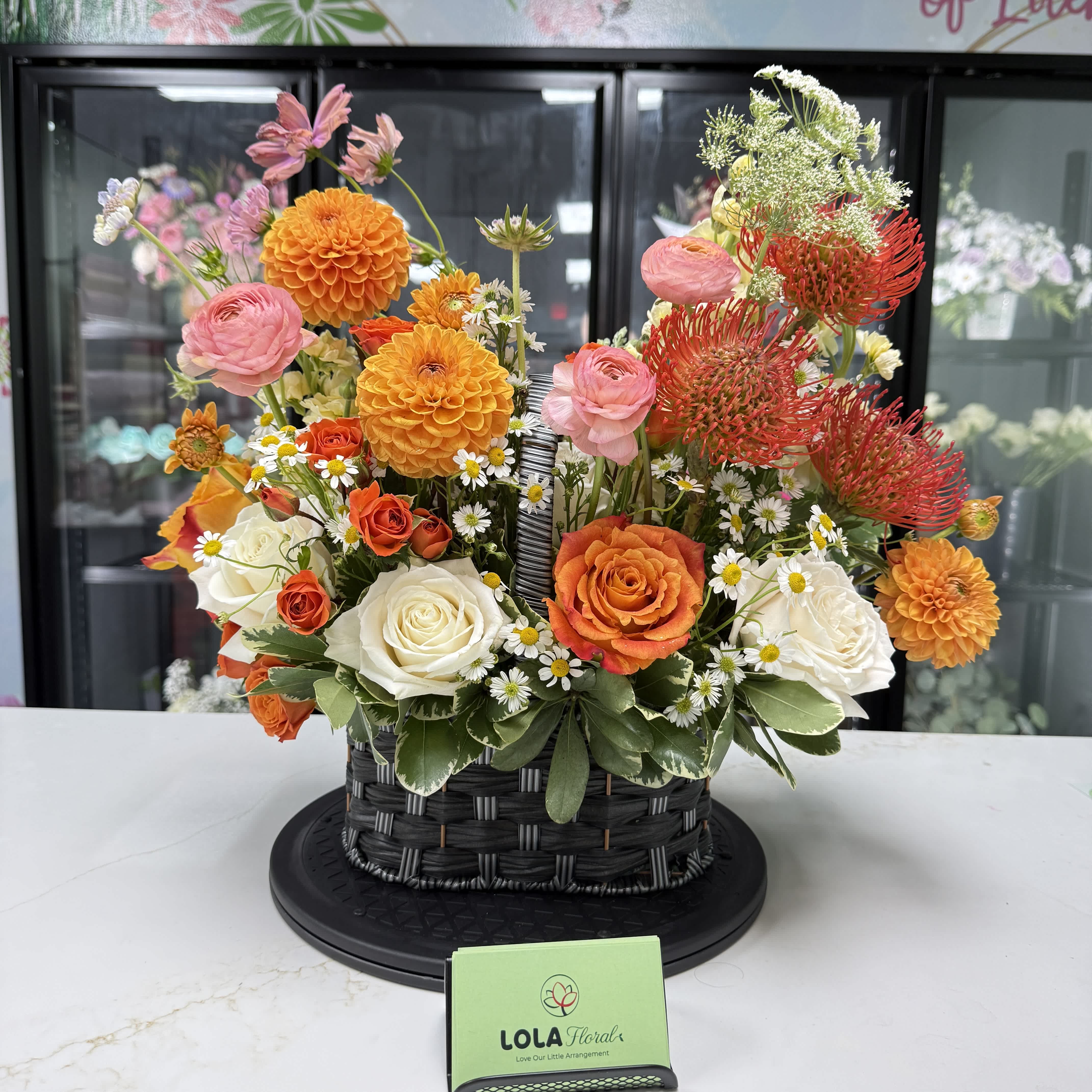 Basket arrangement of orange, pink, and white flowers