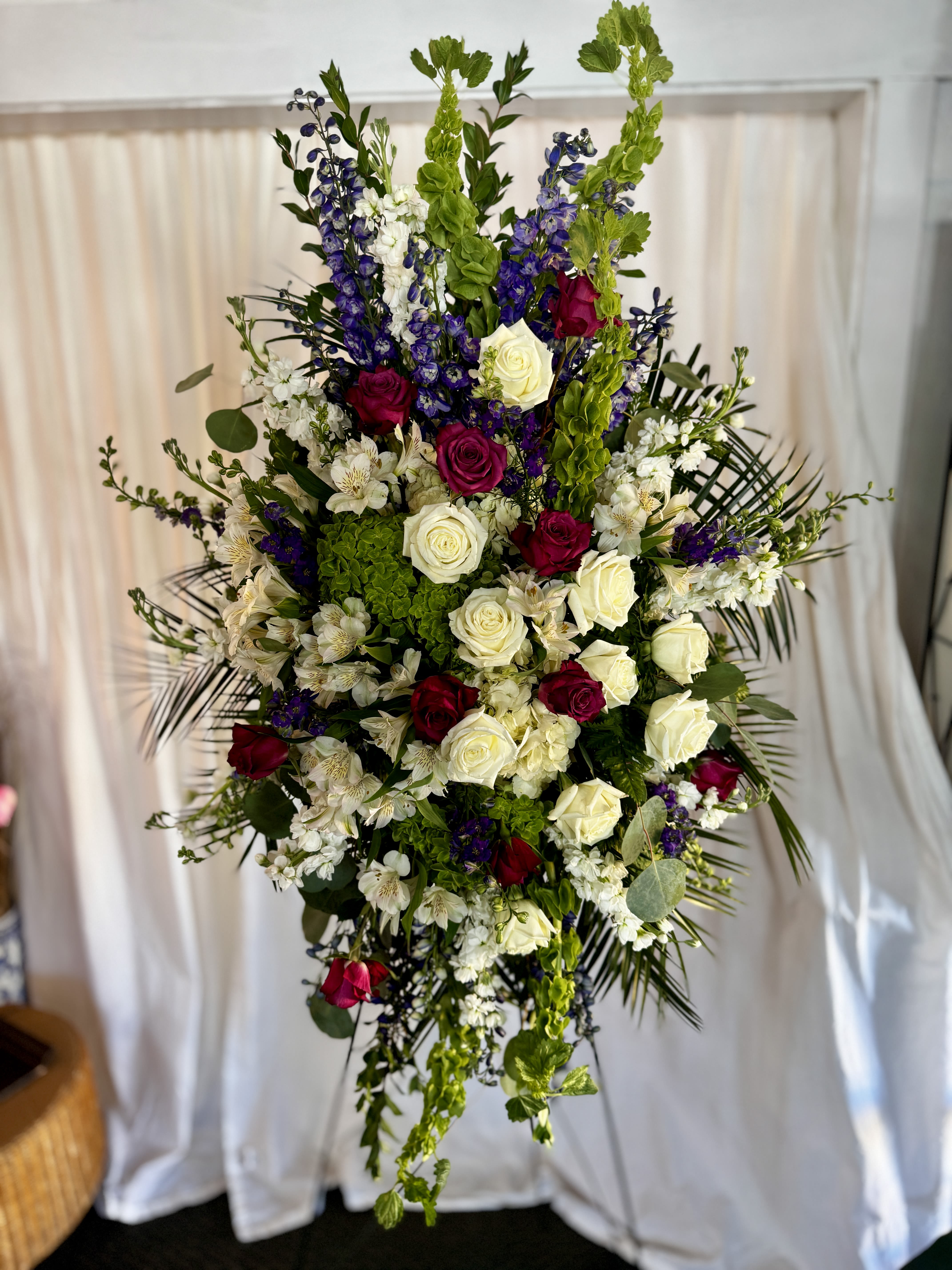 Tall floral spray with red and white roses, purple blooms, and green accents