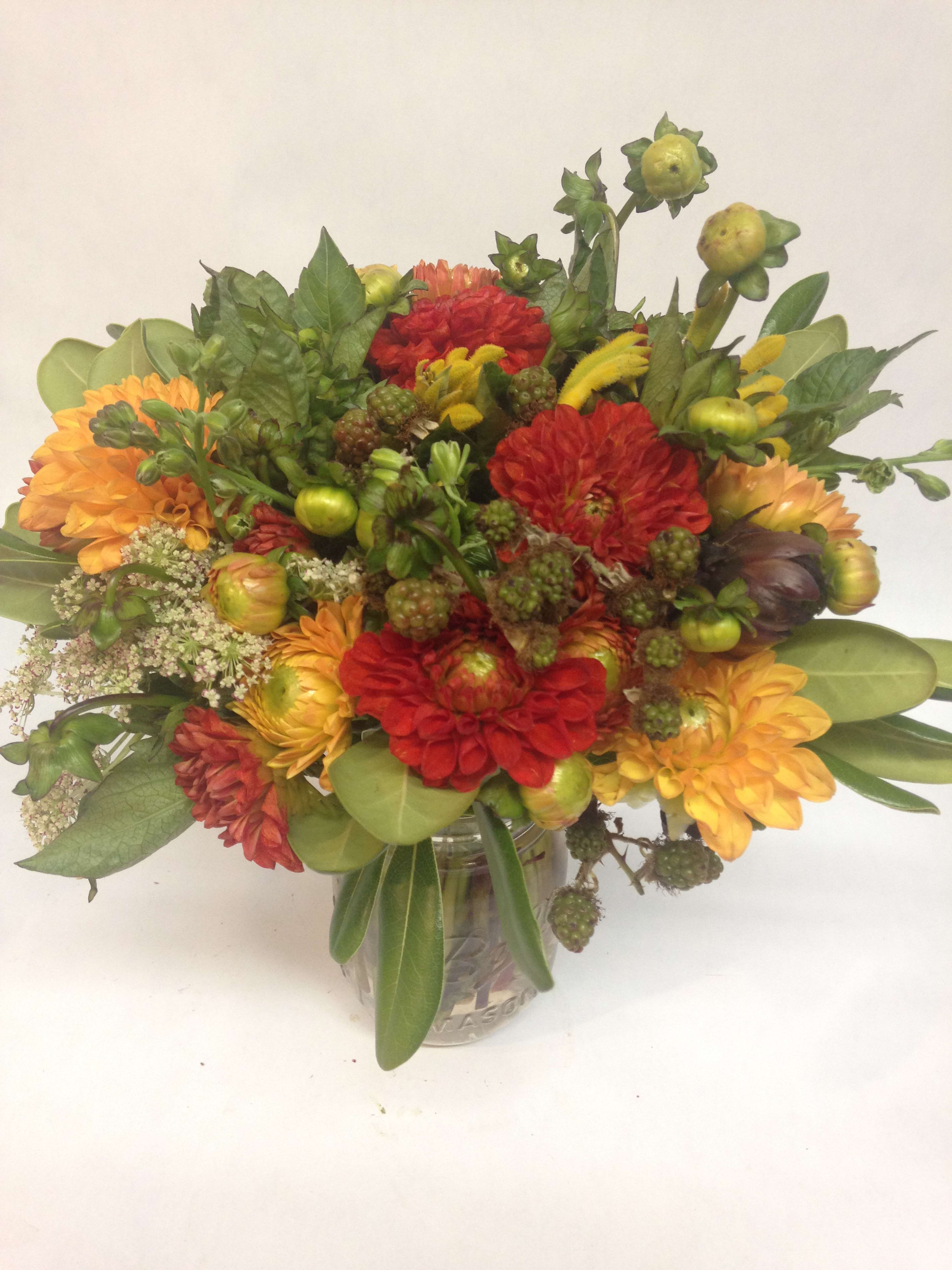 Mixed bouquet of red and orange flowers in a glass vase
