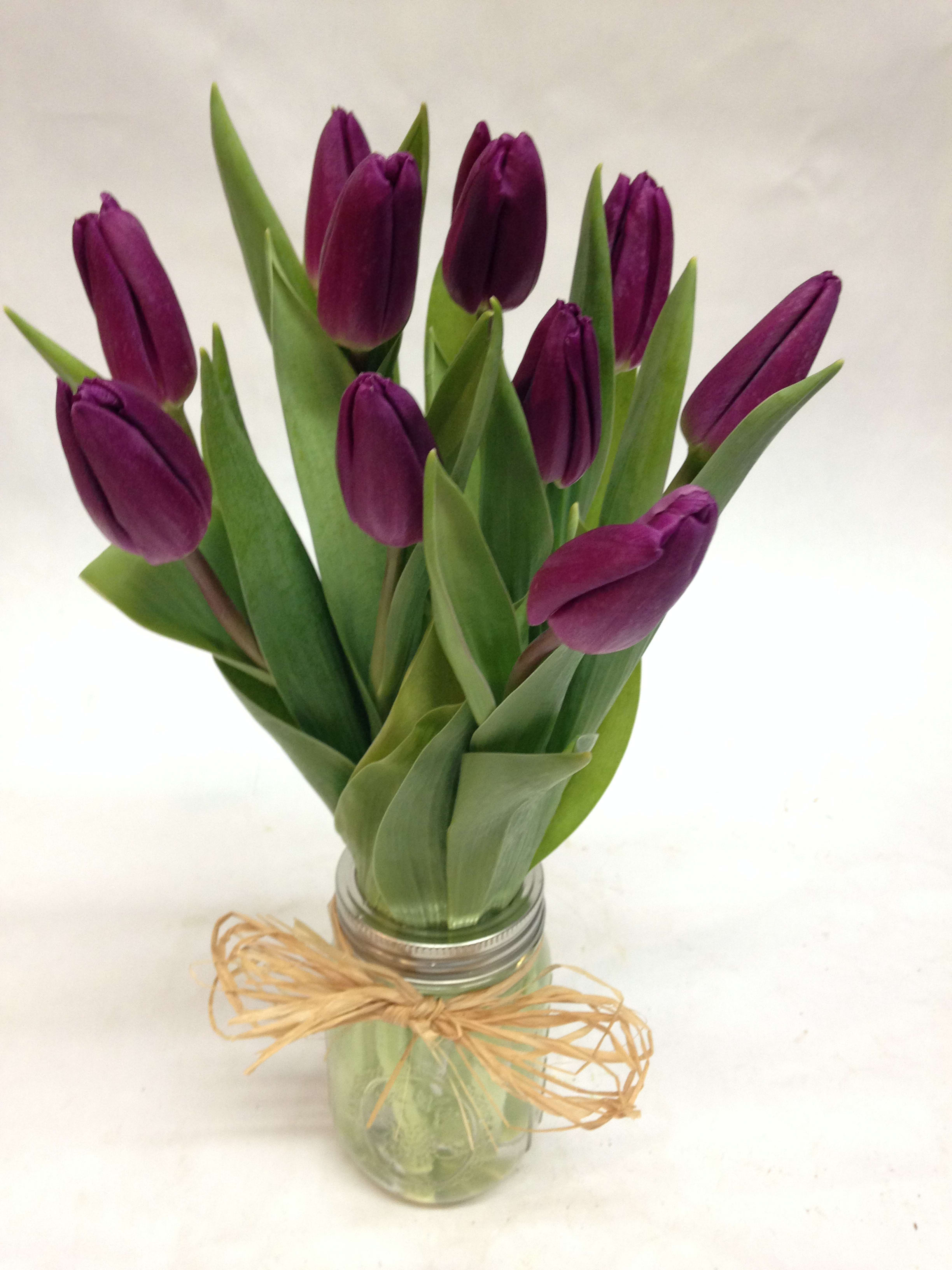 Purple tulips in a glass jar tied with raffia