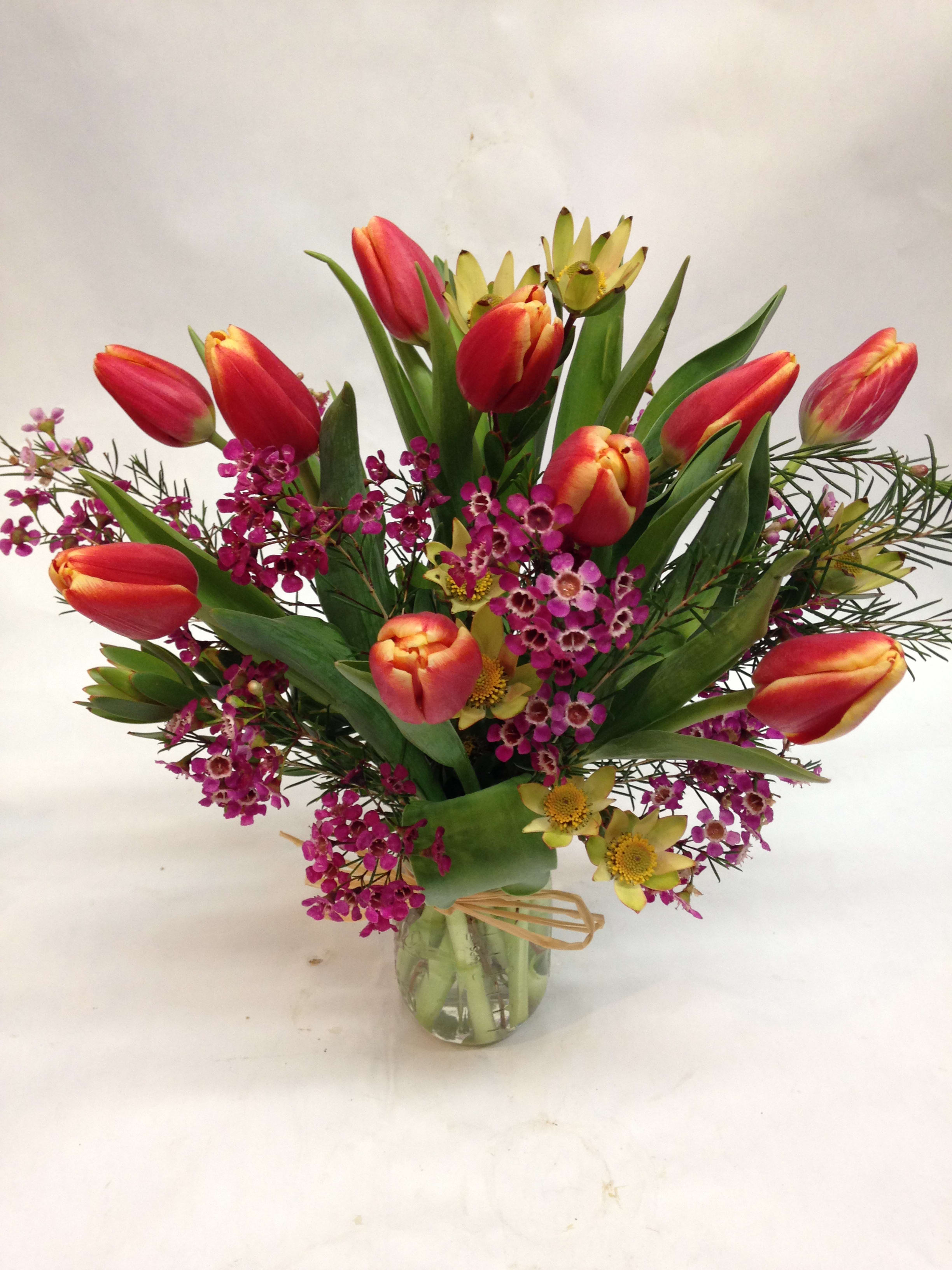 Bouquet of red tulips and purple filler flowers in a glass vase
