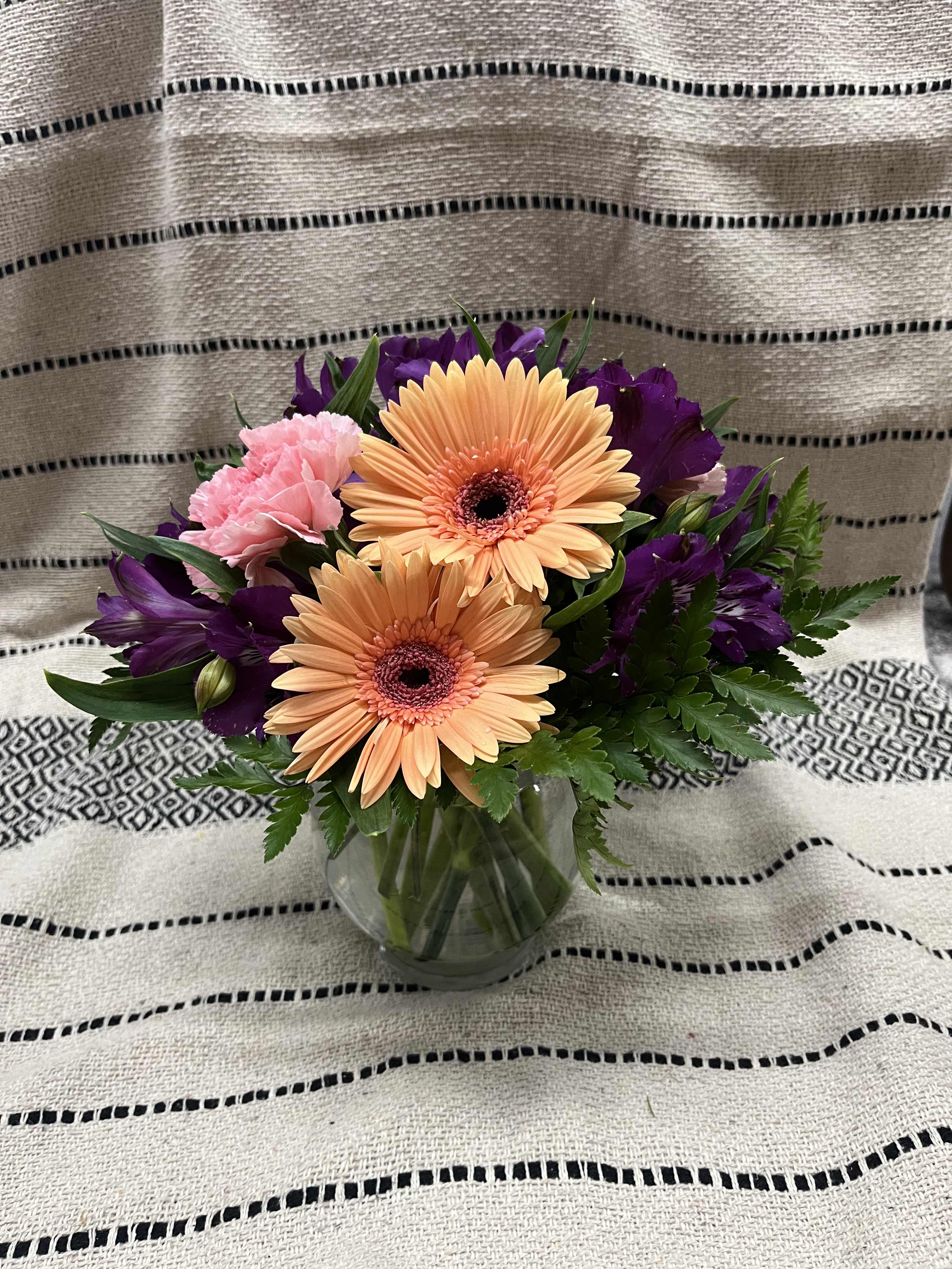 Bouquet of peach gerbera daisies and pink carnations in a glass vase
