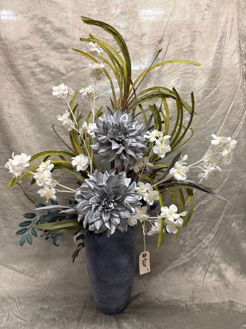 Tall floral arrangement with silver flowers and white blossoms in a dark vase