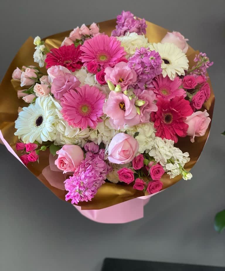 Pink and white mixed bouquet with gerbera daisies and roses wrapped in gold paper