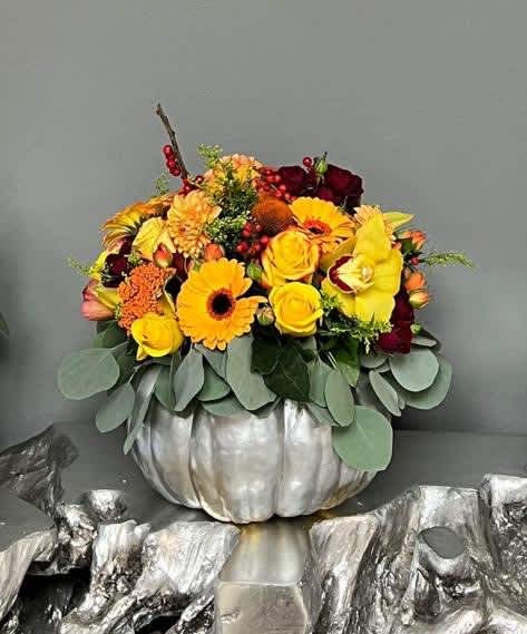 Yellow and burgundy floral arrangement in a silver pumpkin container