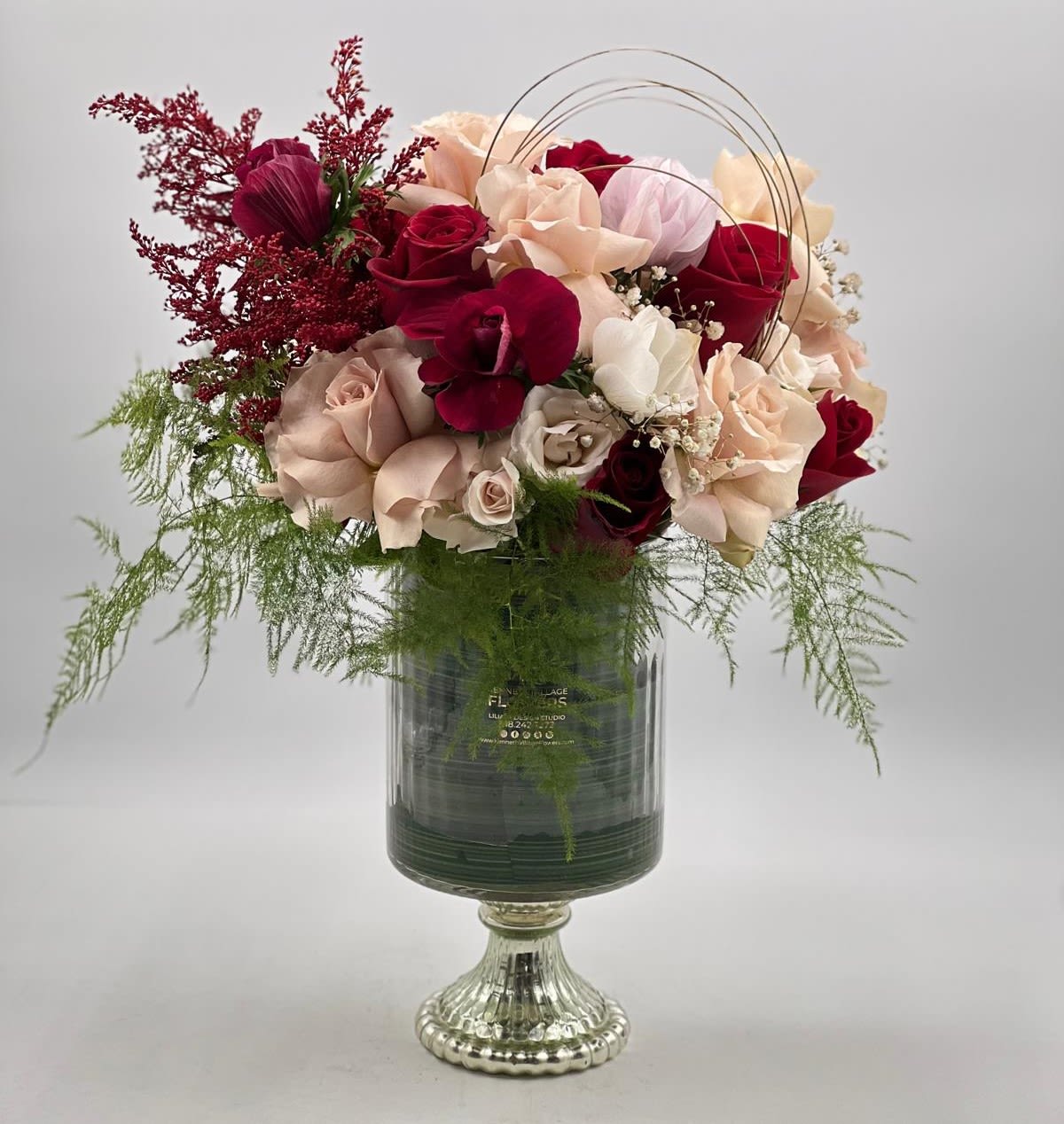Bouquet of red, blush, and cream roses in a glass vase