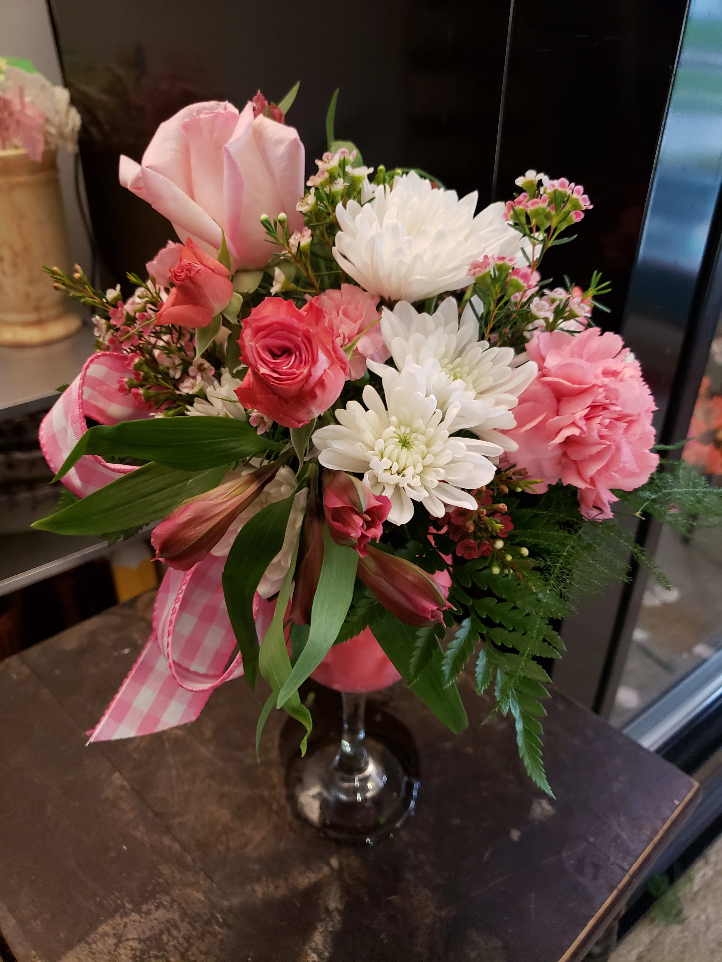 Pink and white mixed bouquet in a clear glass vase with a pink ribbon