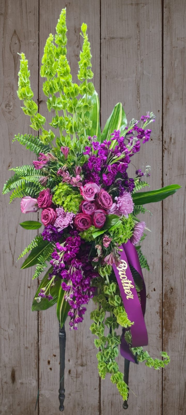 Tall standing floral spray with pink and purple flowers and a ribbon