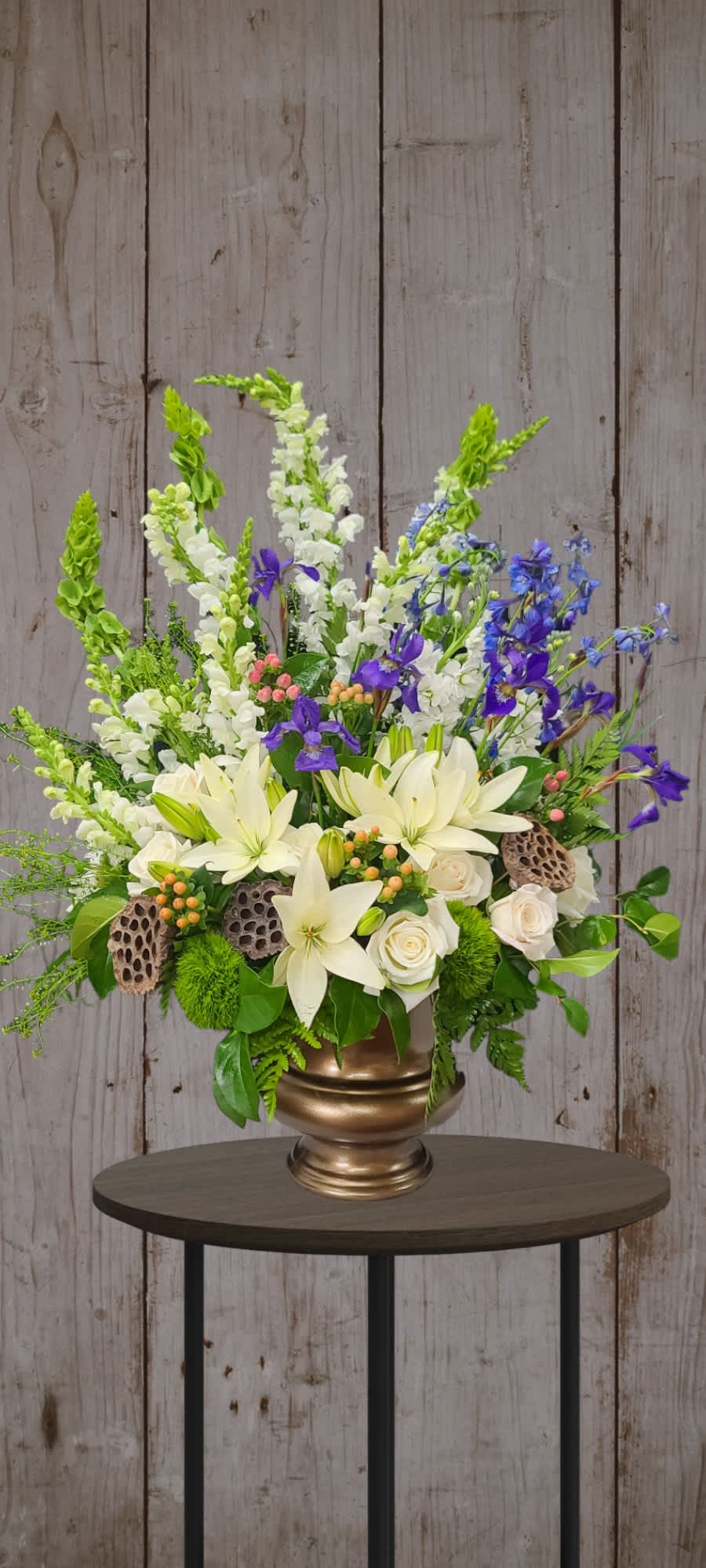White lilies and roses with purple and blue flowers in a gold vase