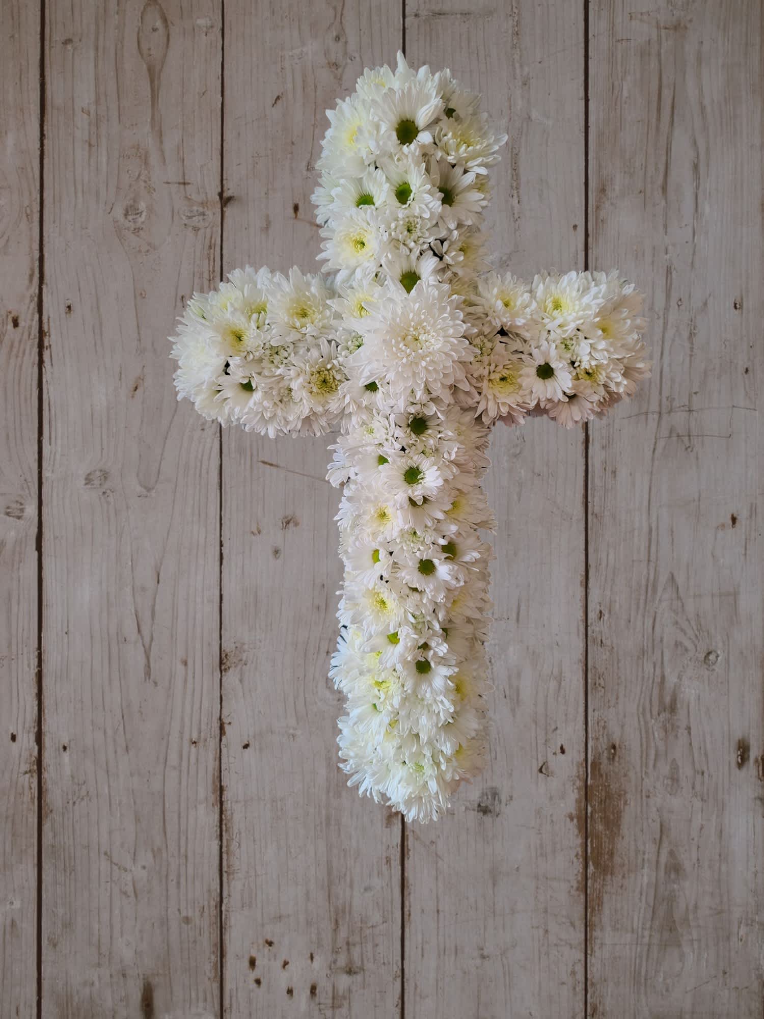 White daisy cross arrangement on a rustic wood background
