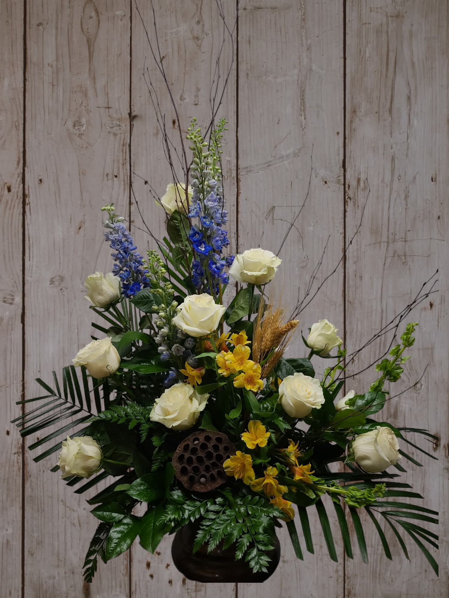 White roses with blue and yellow flowers in a black vase
