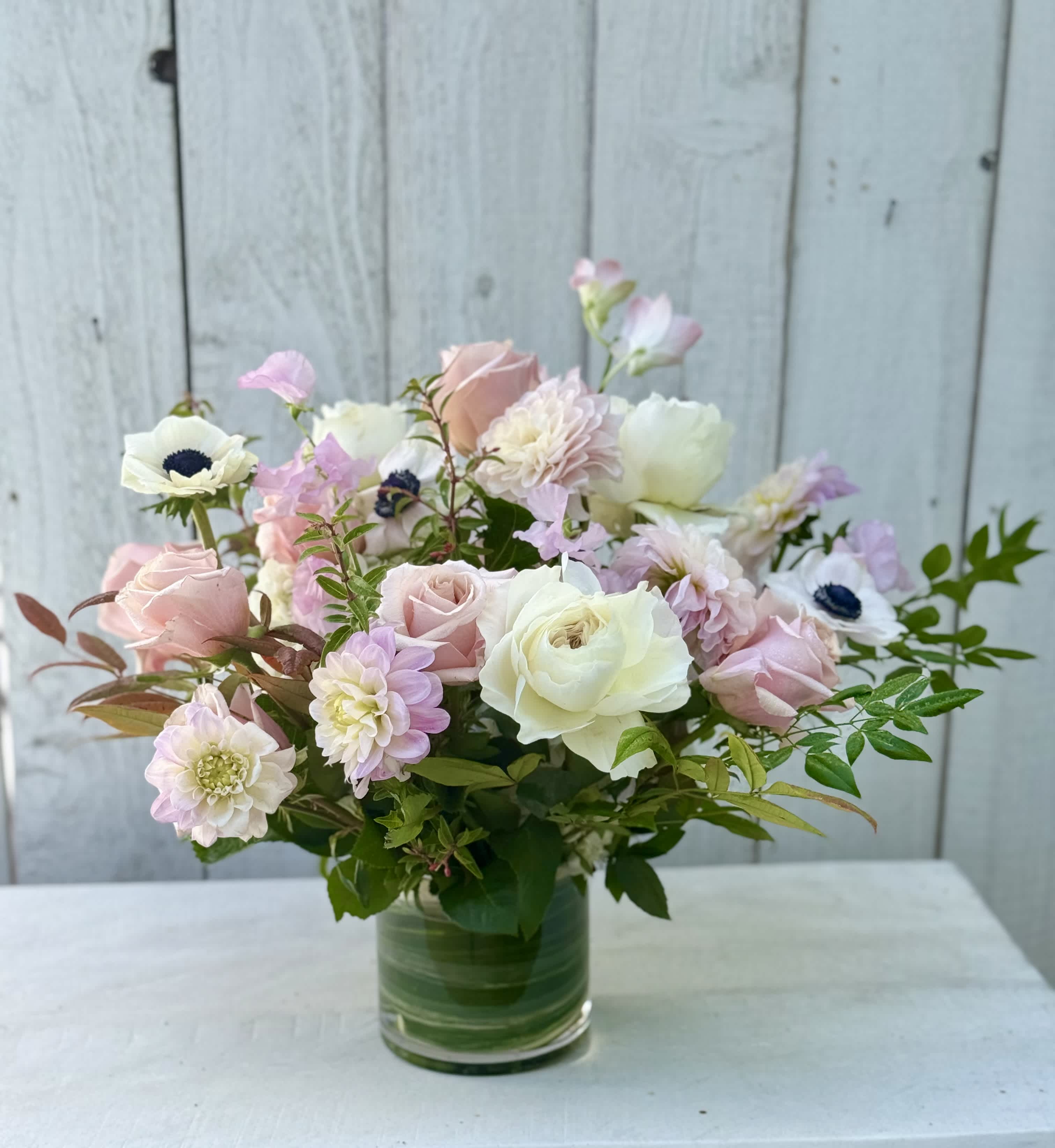 Pastel bouquet of roses and mixed blooms in a clear glass vase