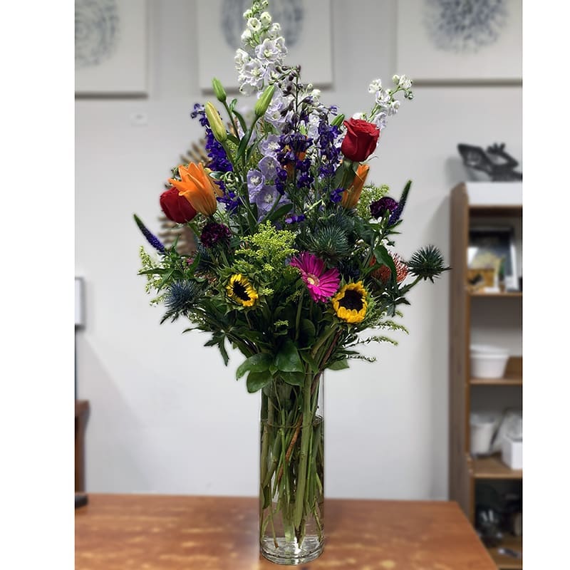 Tall mixed bouquet in a clear glass vase with colorful blooms