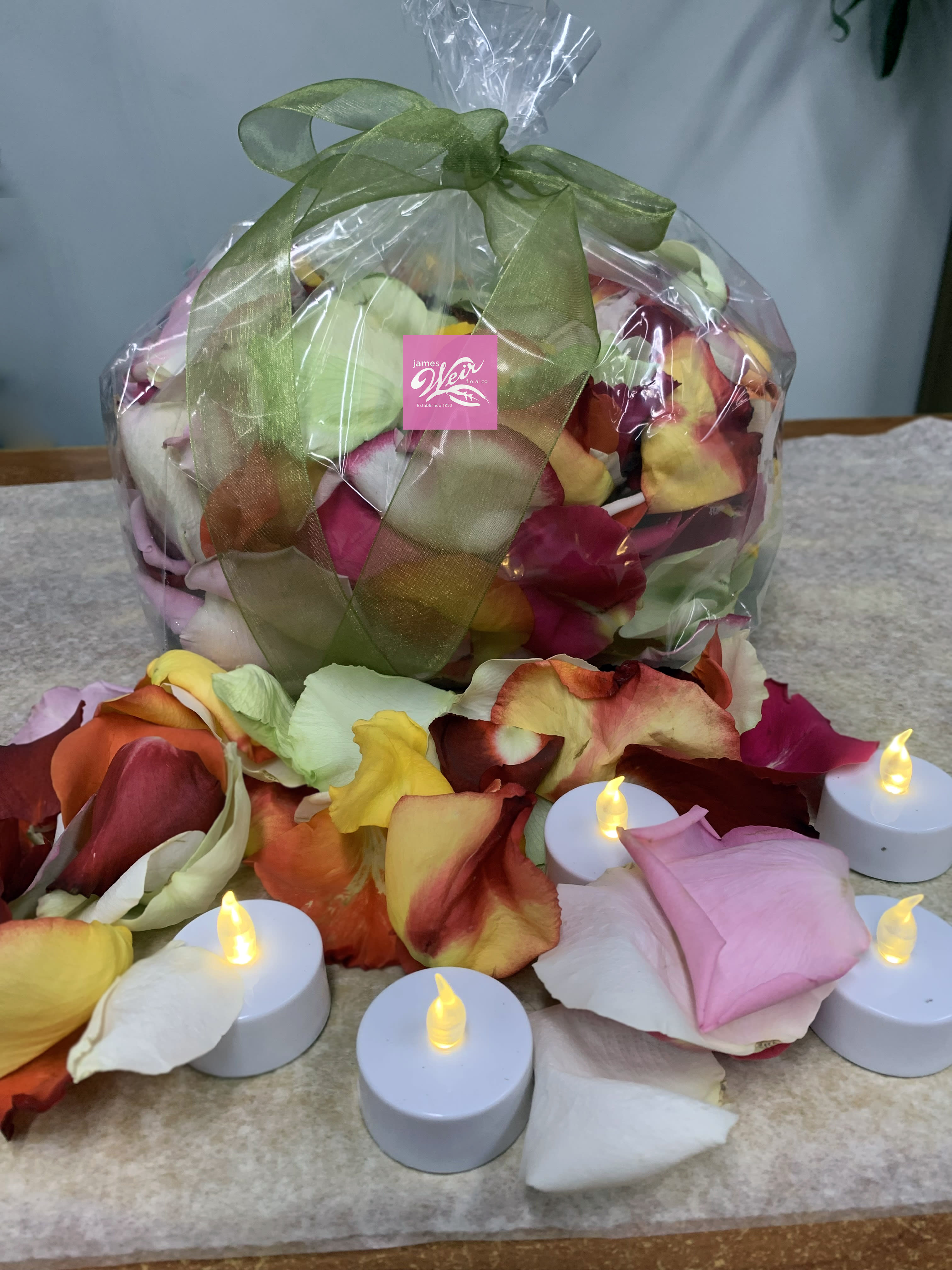 Wrapped bundle of multicolored rose petals with small LED tealights