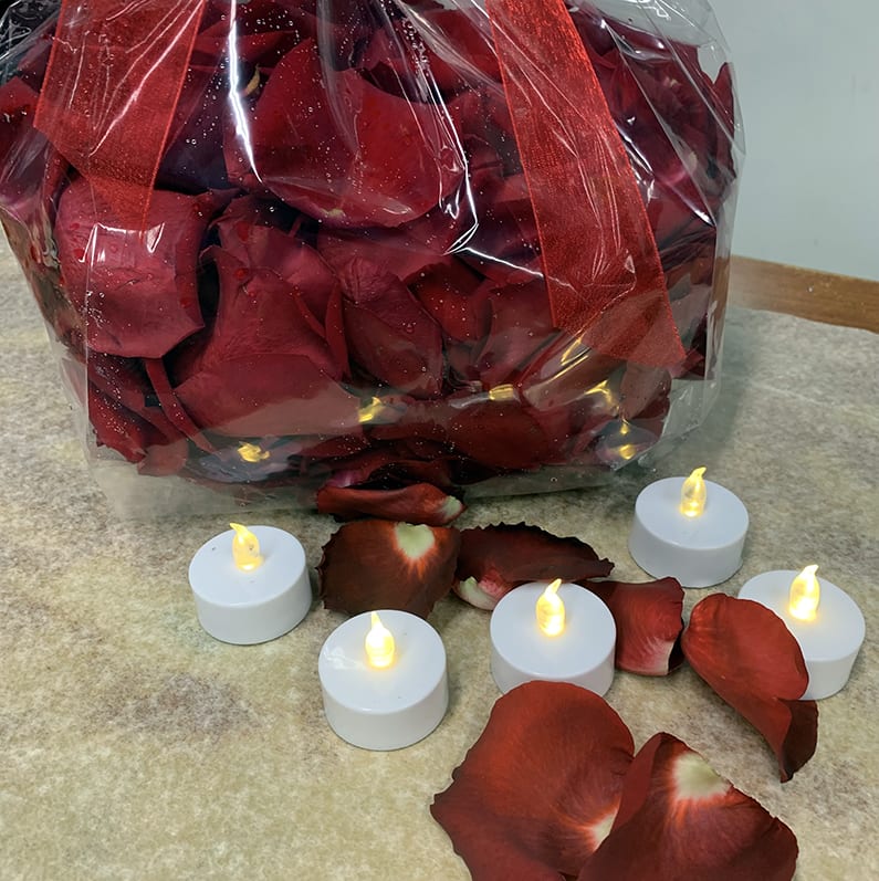Bag of red rose petals with small LED tealight candles