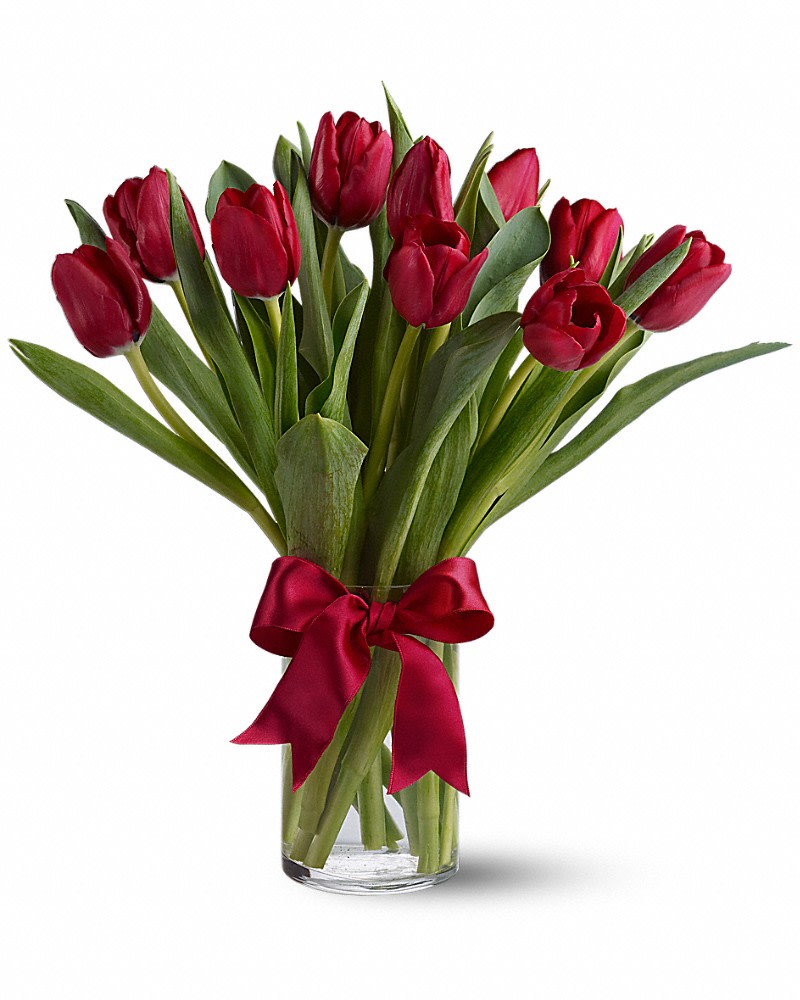 Red tulips in a clear glass vase tied with a red ribbon
