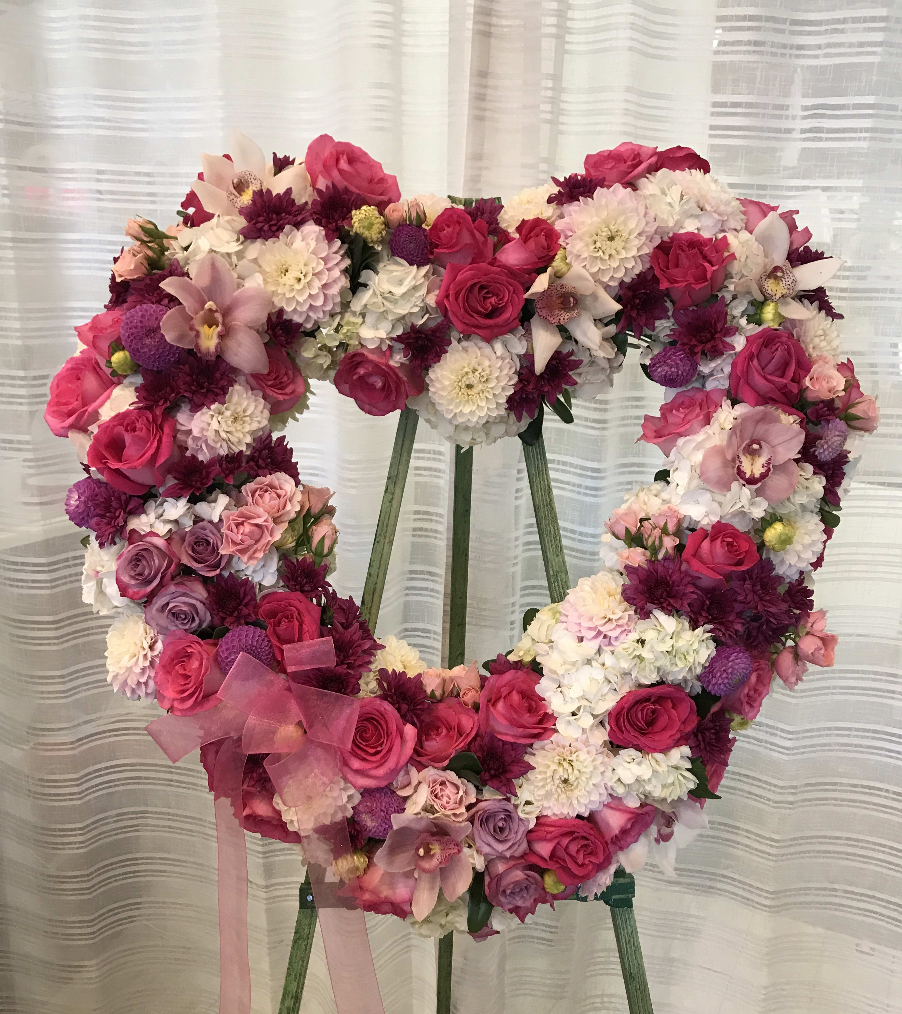 Heart-shaped floral wreath with pink and white flowers on an easel