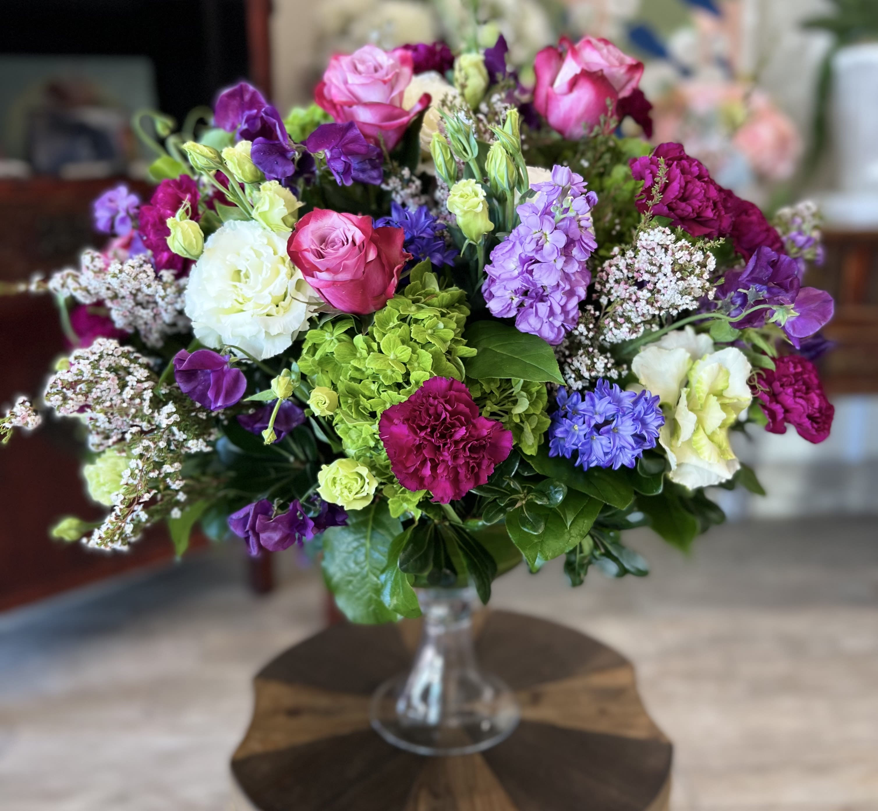 Mixed bouquet of pink, purple, white, and green flowers in a glass vase