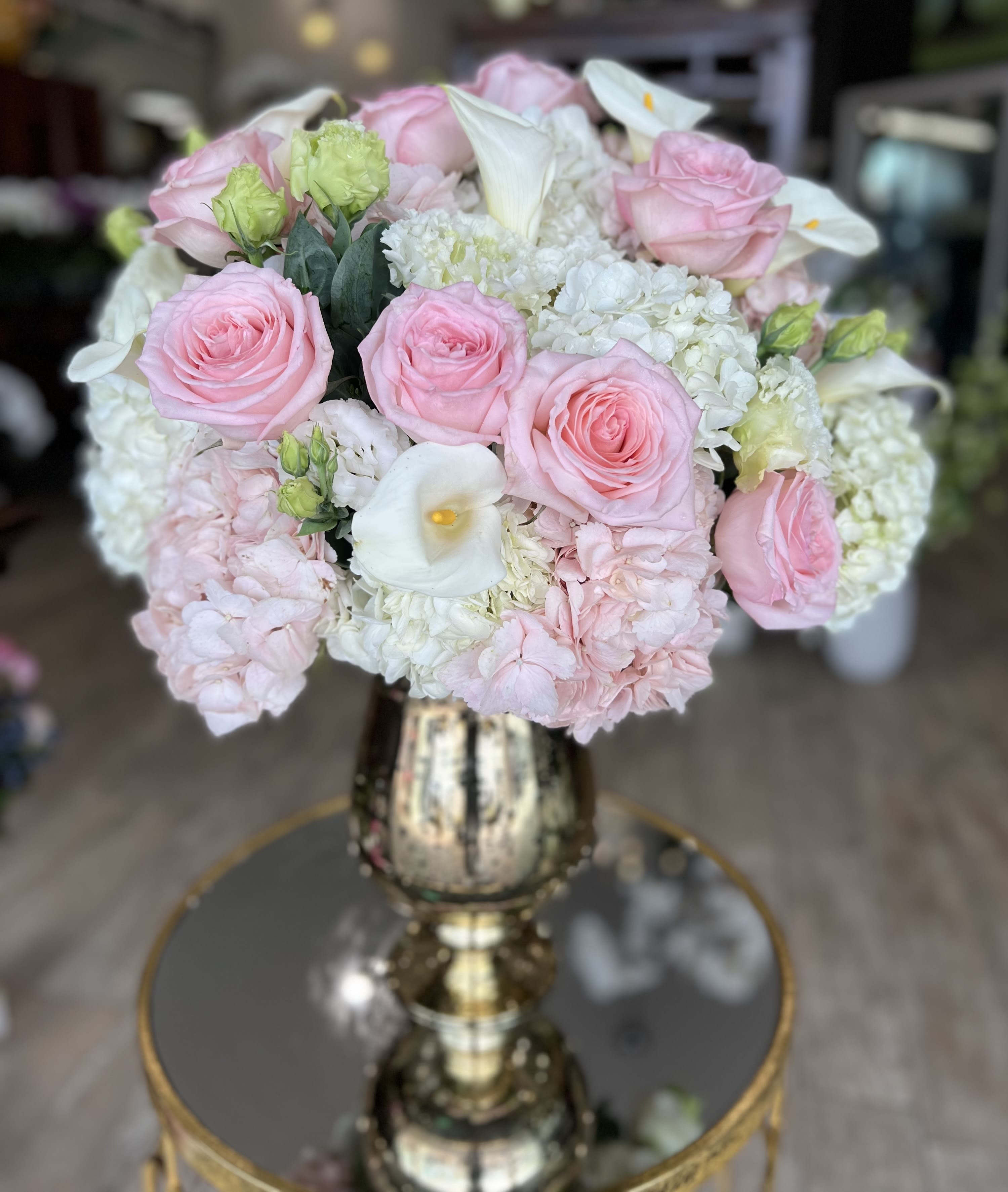 Pink roses and white calla lilies arranged in a gold vase