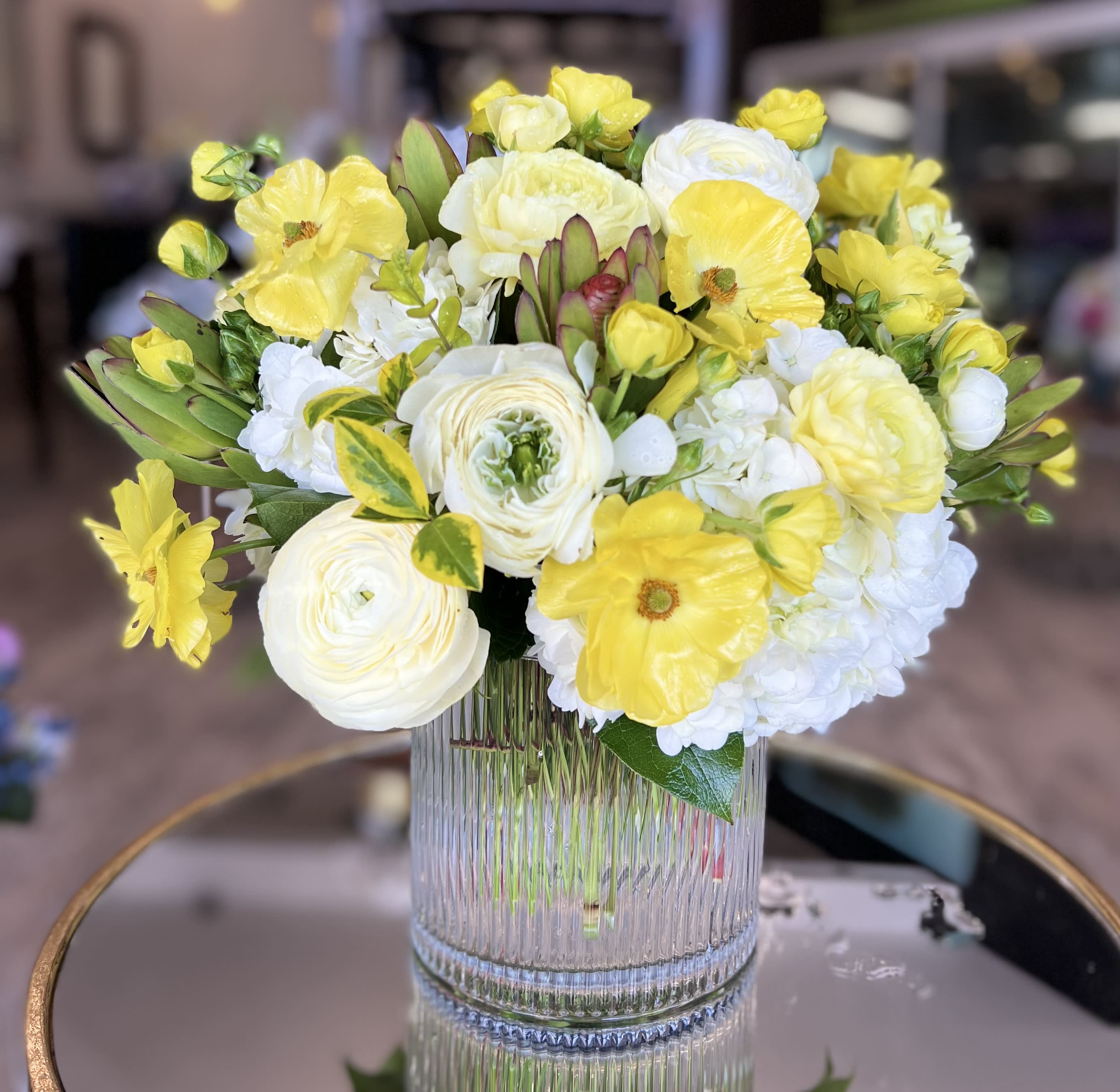 Yellow and white flower arrangement in a clear ribbed vase