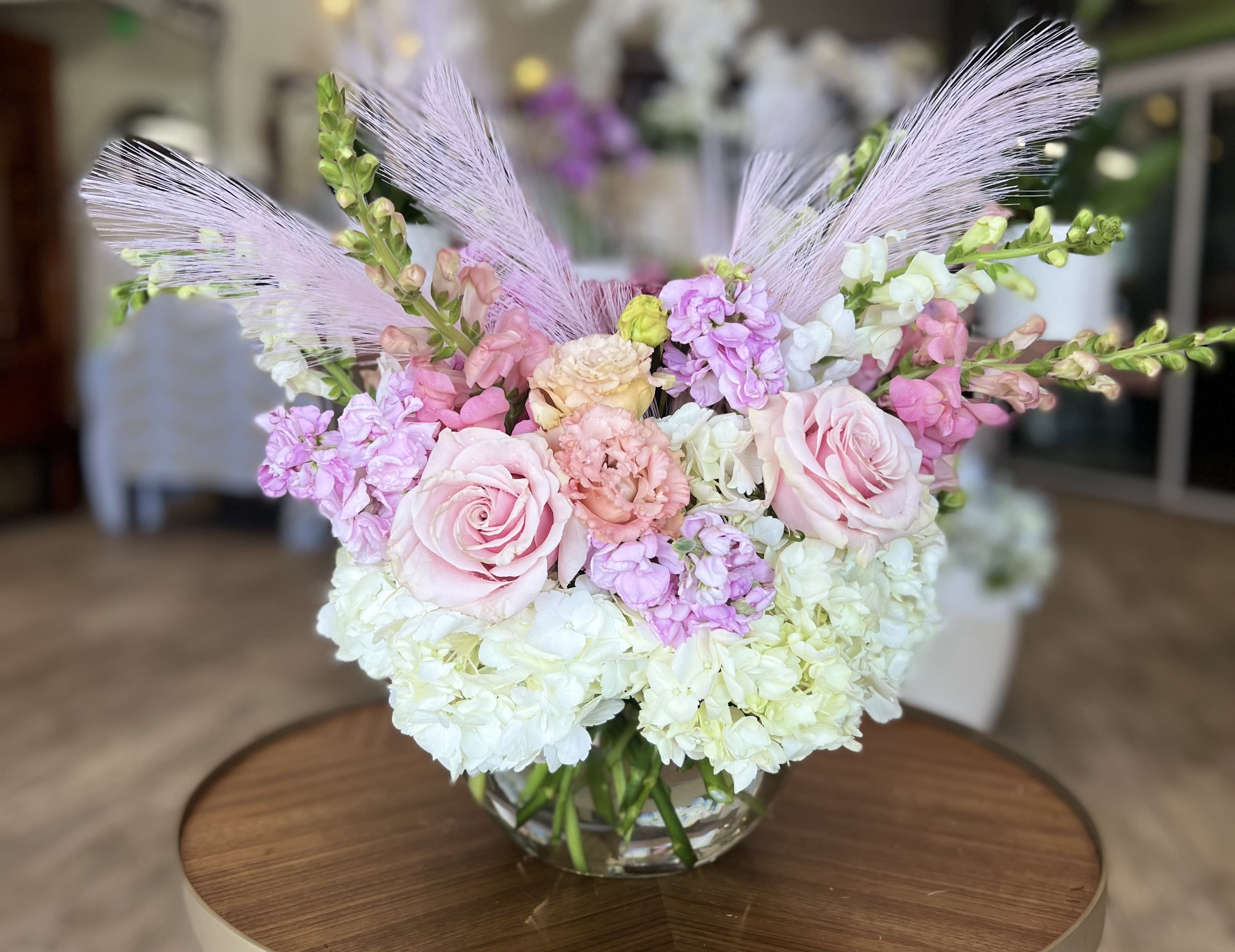 Pink roses and pastel flowers arranged in a clear glass vase