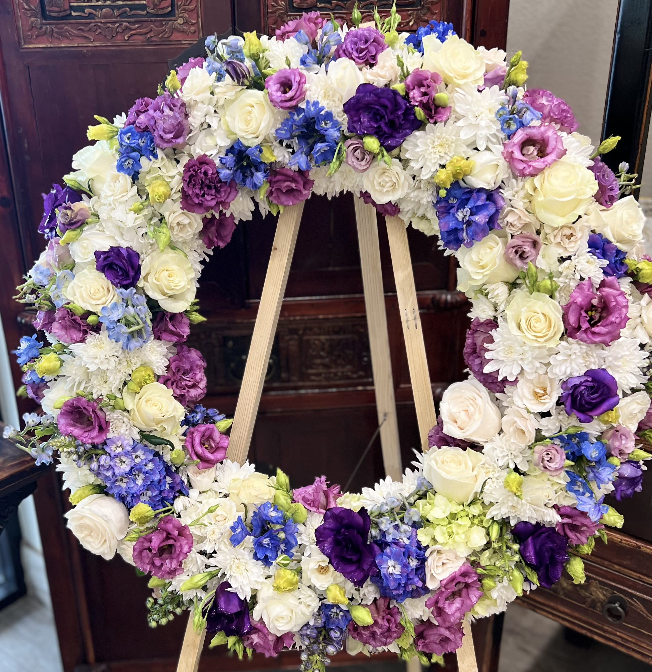 Large floral wreath with white, purple, pink, and blue blooms on an easel