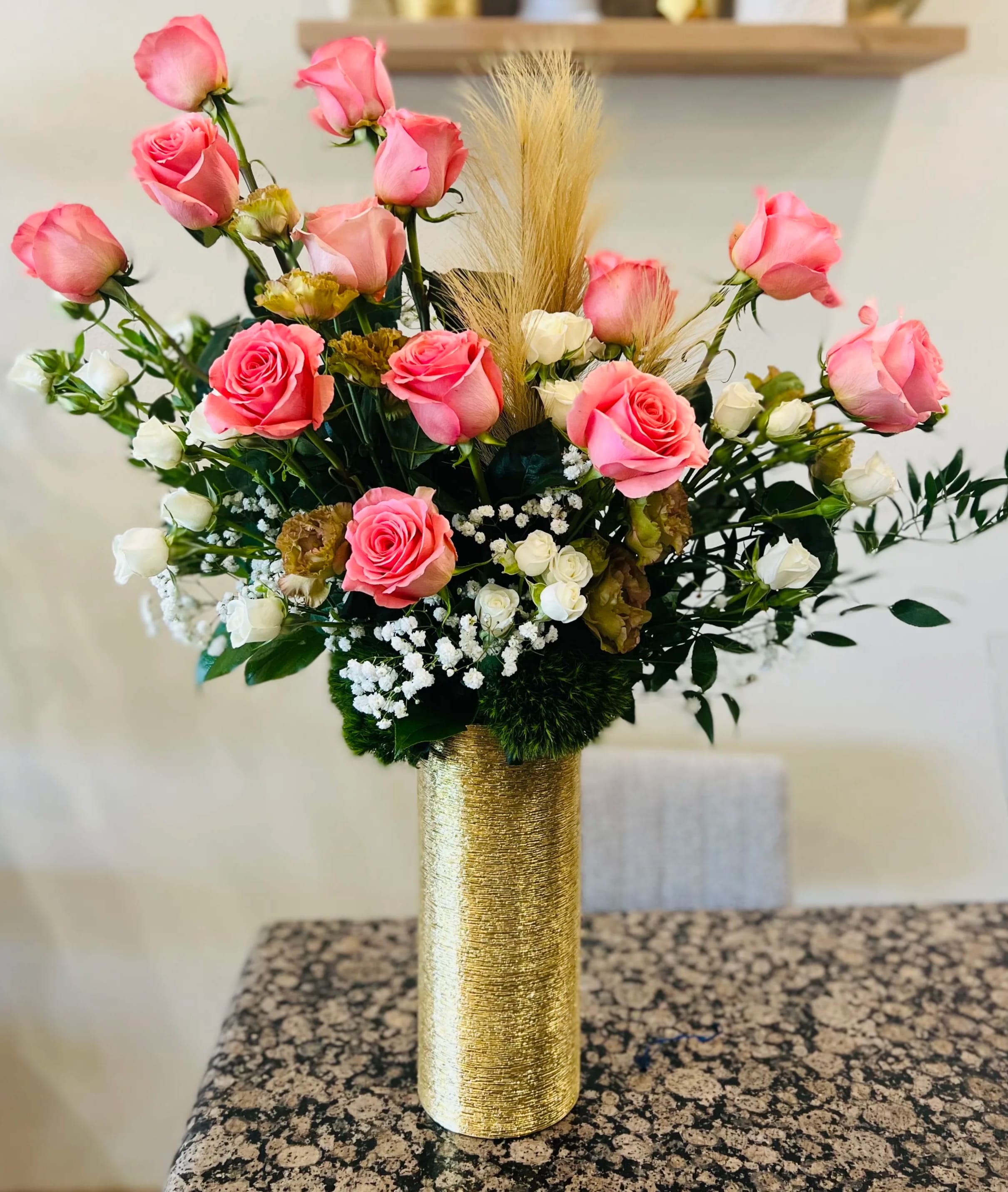 Pink and white roses arranged in a gold vase