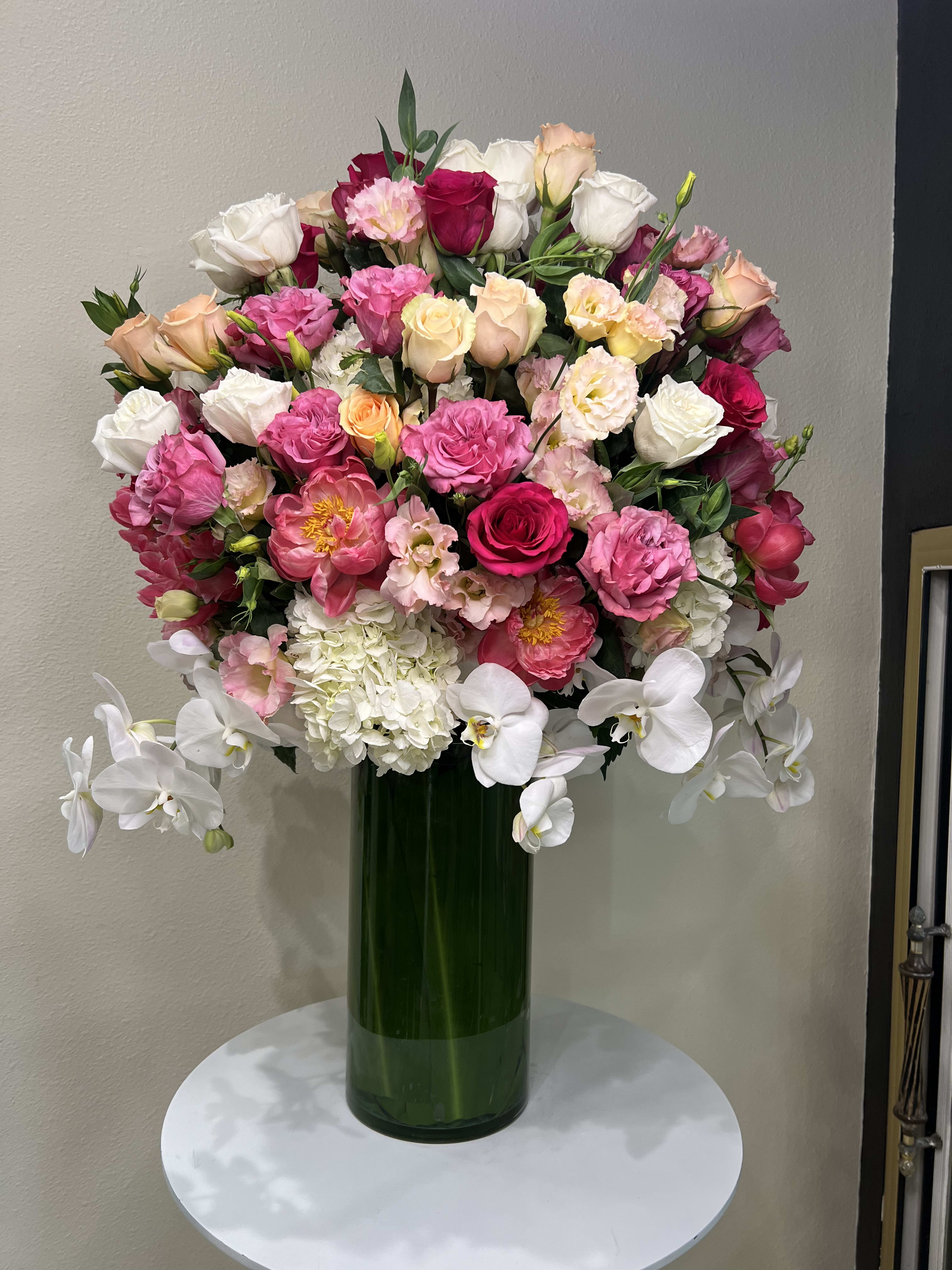 Large bouquet of pink, white, and peach flowers in a tall green vase