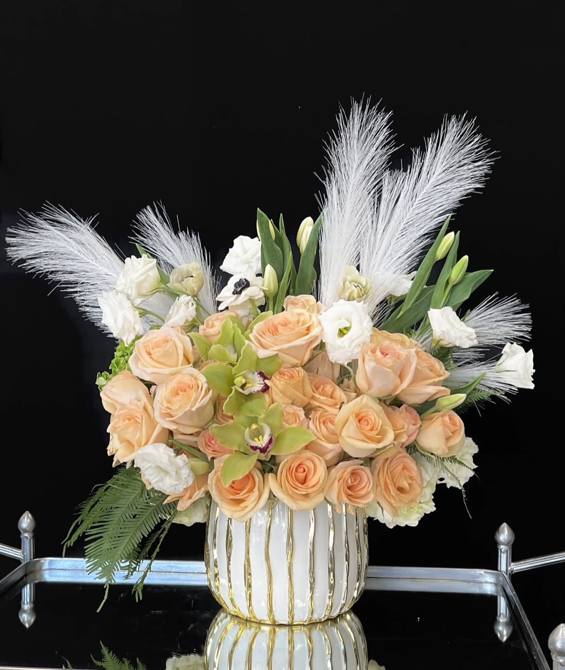 Peach roses and white flowers in a white-and-gold vase