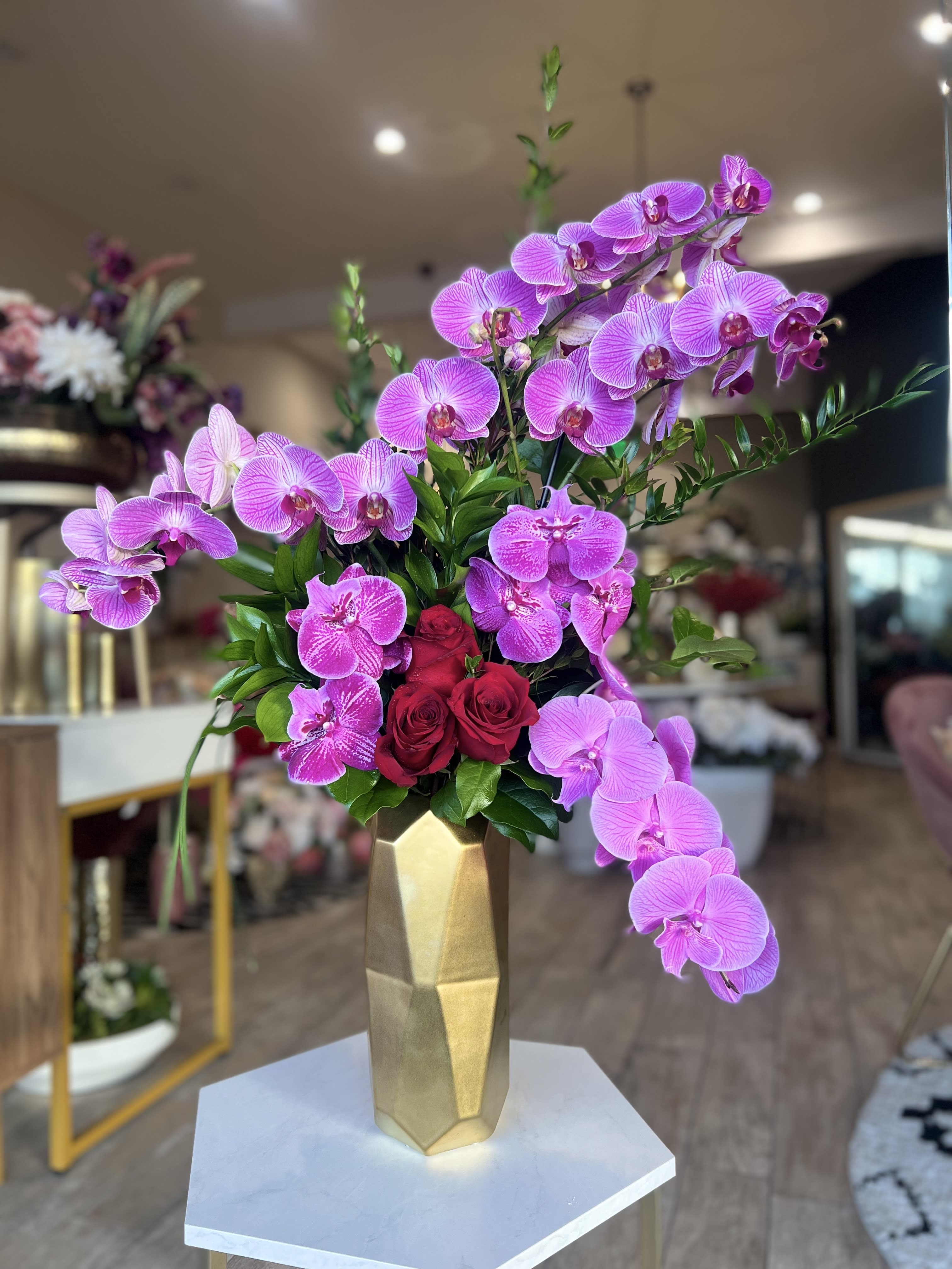 Pink orchids and red roses in a gold vase
