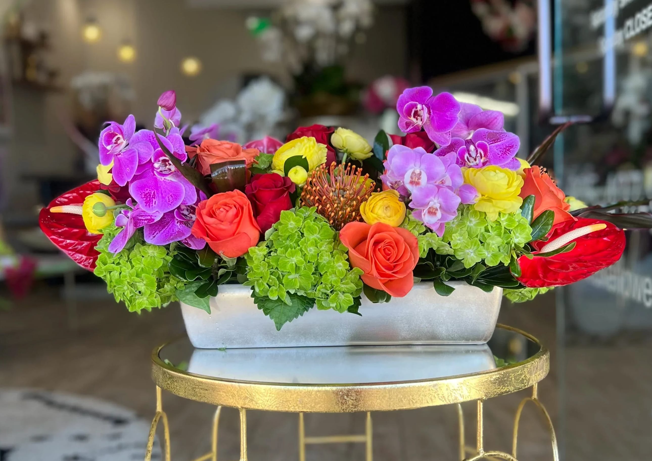 Rectangular flower arrangement with orchids, roses, and hydrangeas in a white container