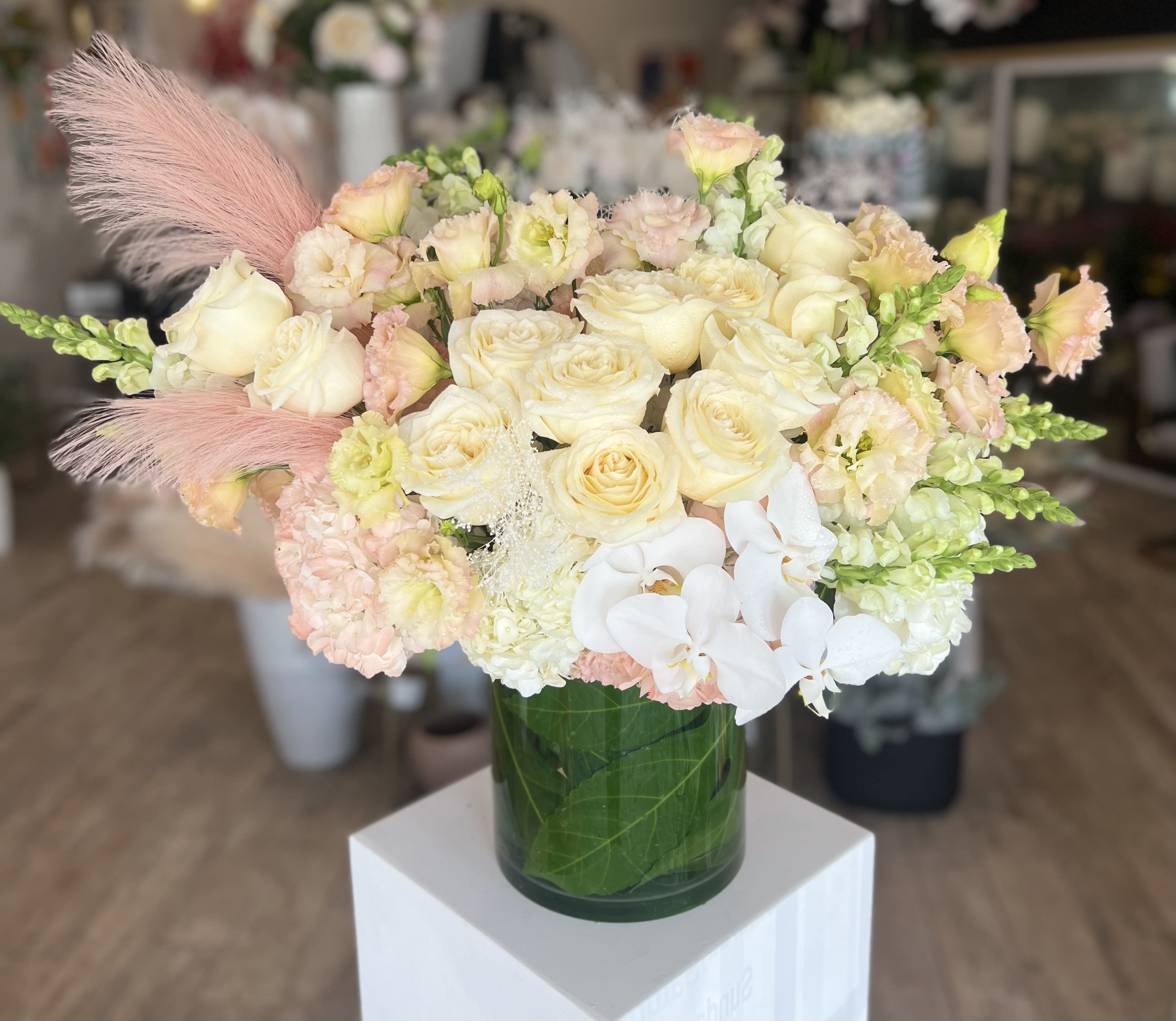 Cream and blush bouquet of roses, orchids, and snapdragons in a glass vase