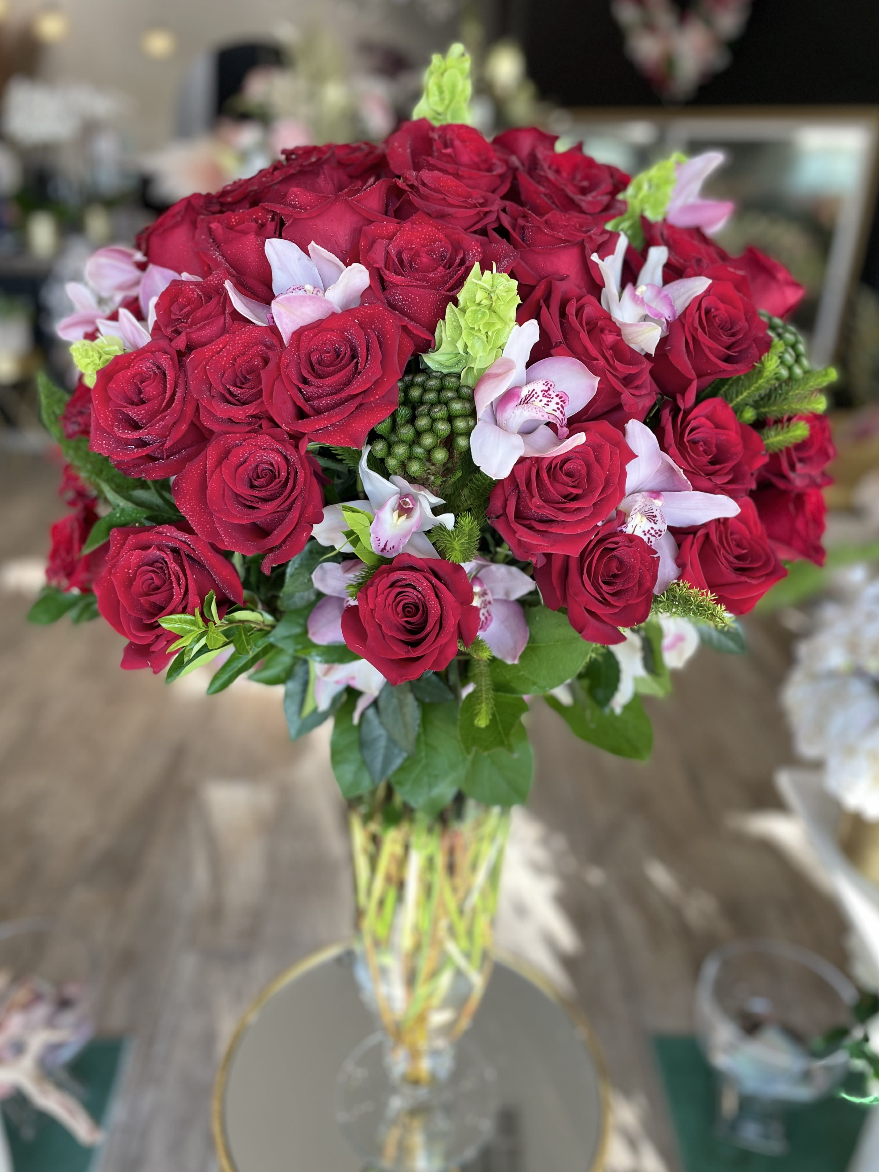 Bouquet of red roses with pale pink orchids in a clear glass vase