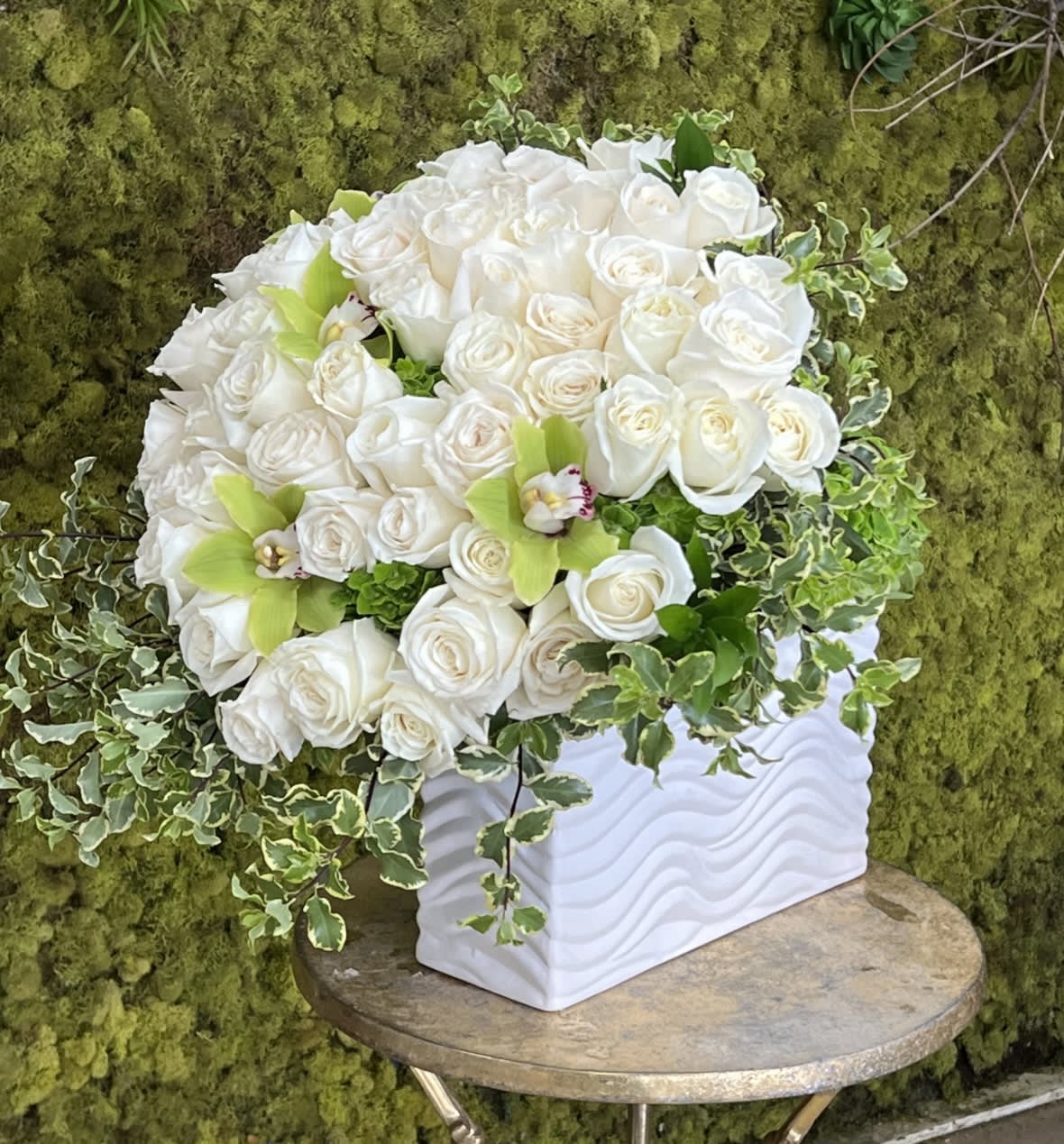 White rose arrangement in a white textured vase with trailing ivy