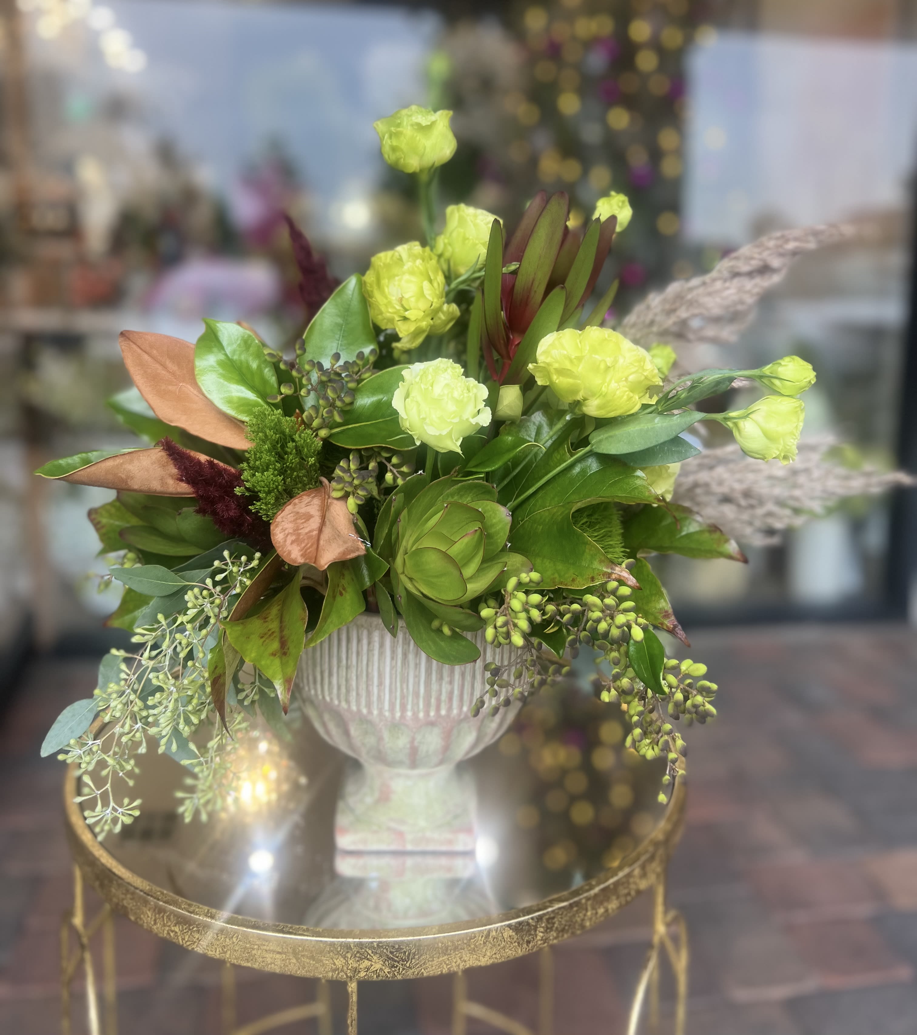 Green and lime floral arrangement in a white pedestal vase