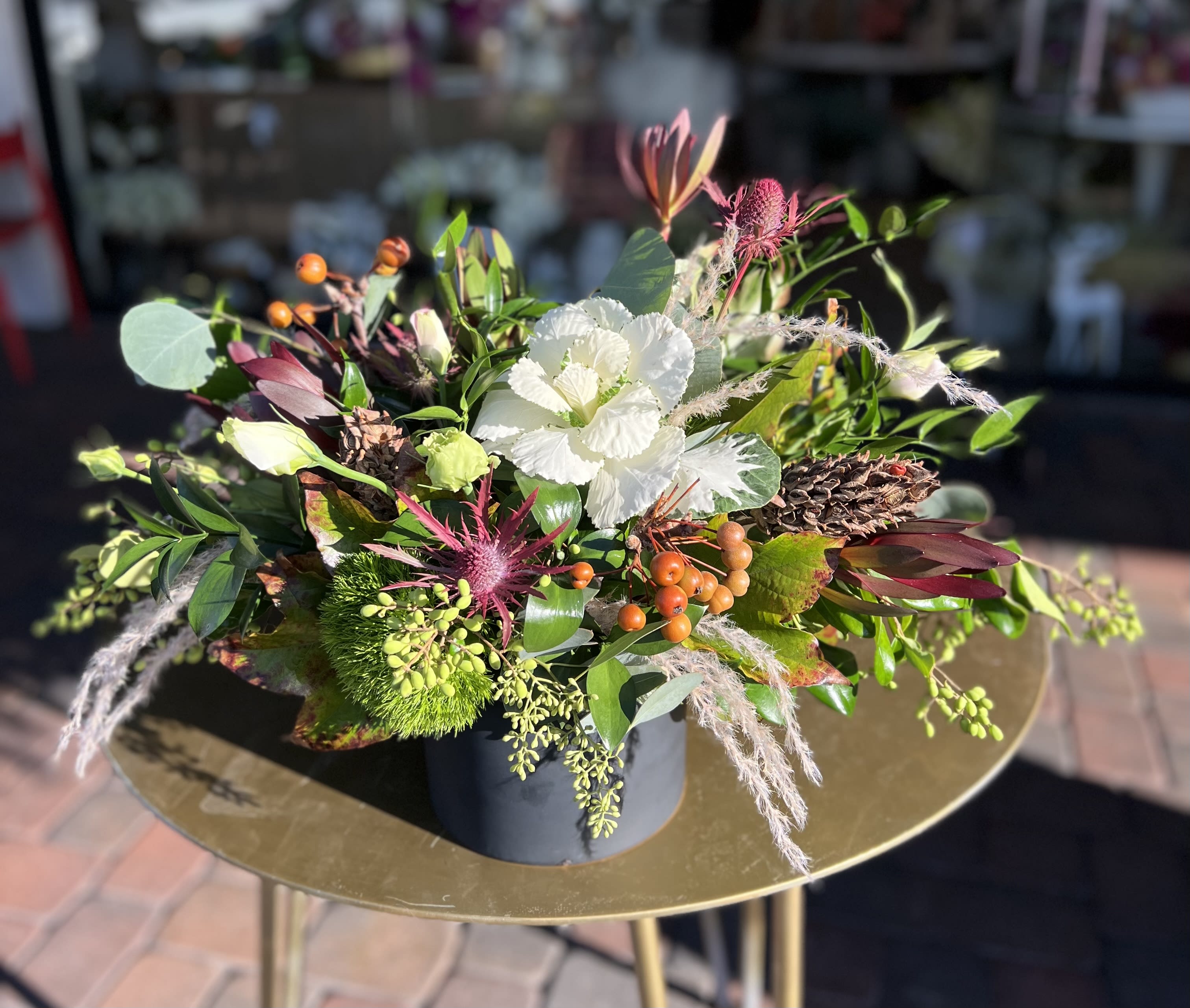 Mixed floral arrangement with white blooms and orange berries in a dark container