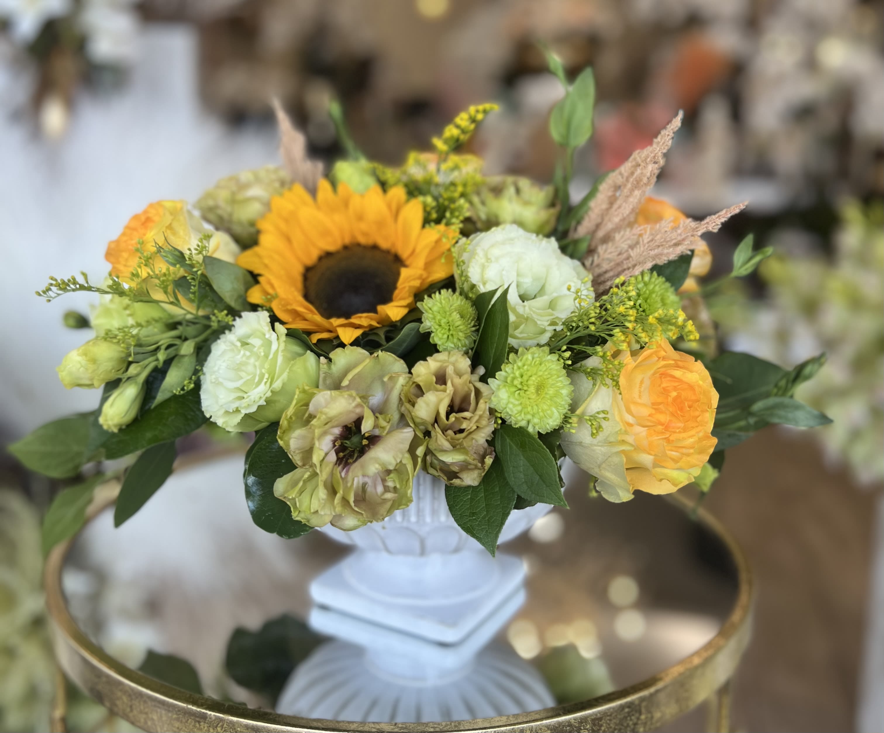 Mixed floral arrangement with a sunflower in a white pedestal vase