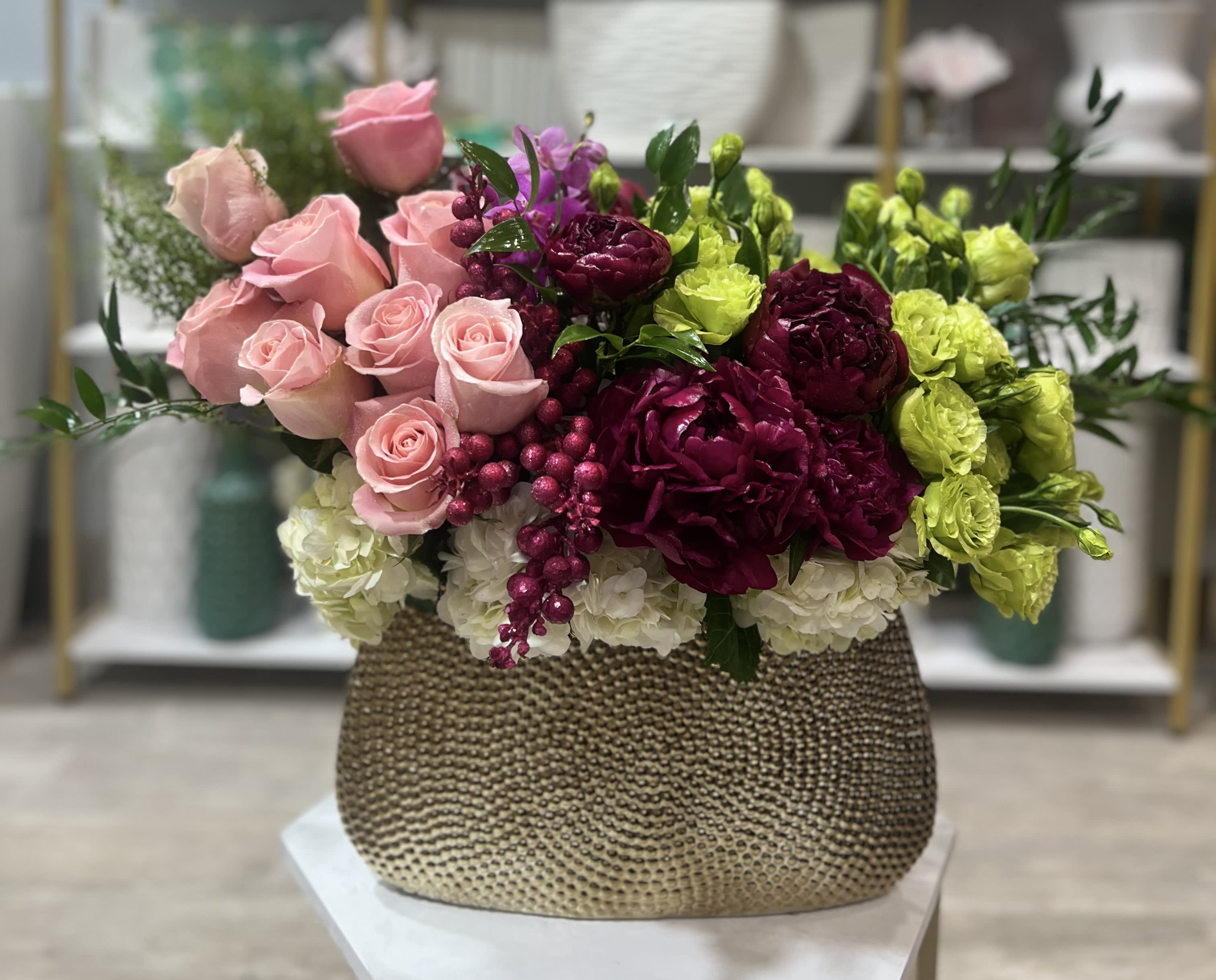 Pink roses and magenta flowers in a textured gold vase
