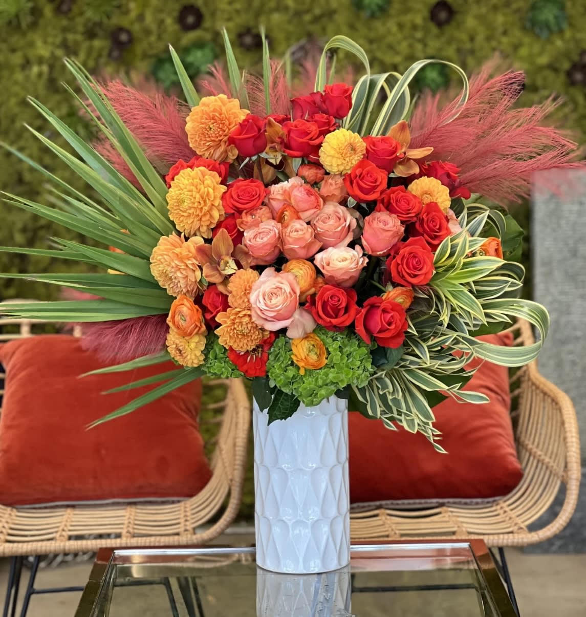 Bright bouquet of red, pink, and orange flowers in a white vase