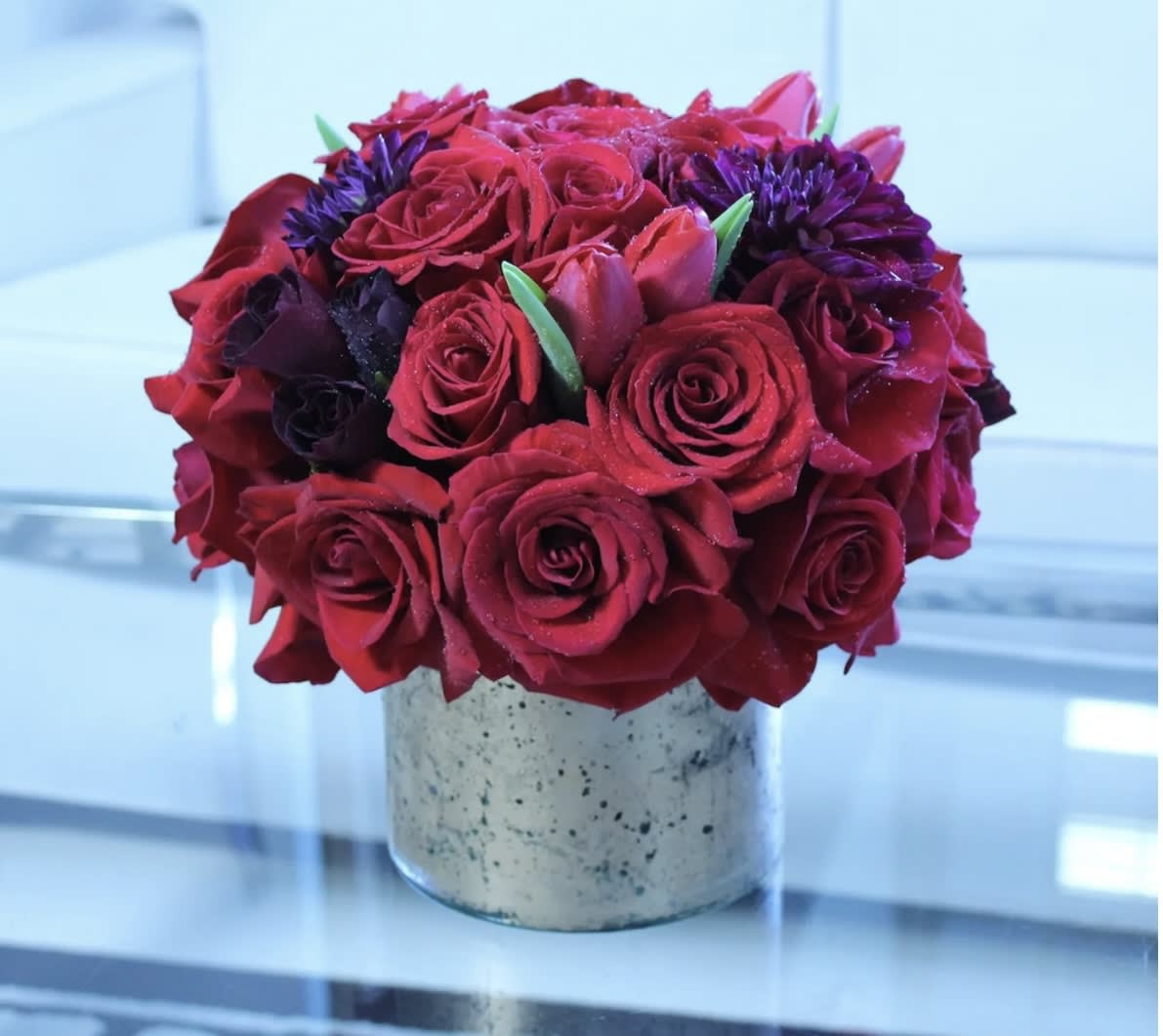 Red rose bouquet with purple flowers in a speckled vase