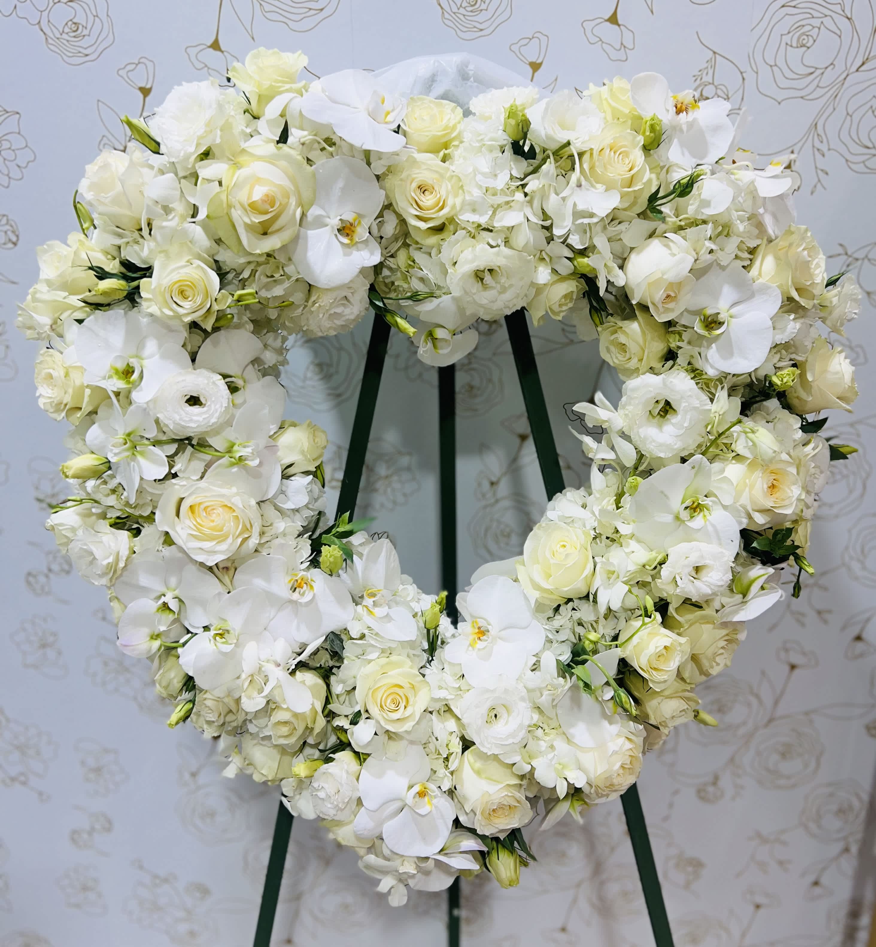 Heart-shaped white floral wreath on a stand