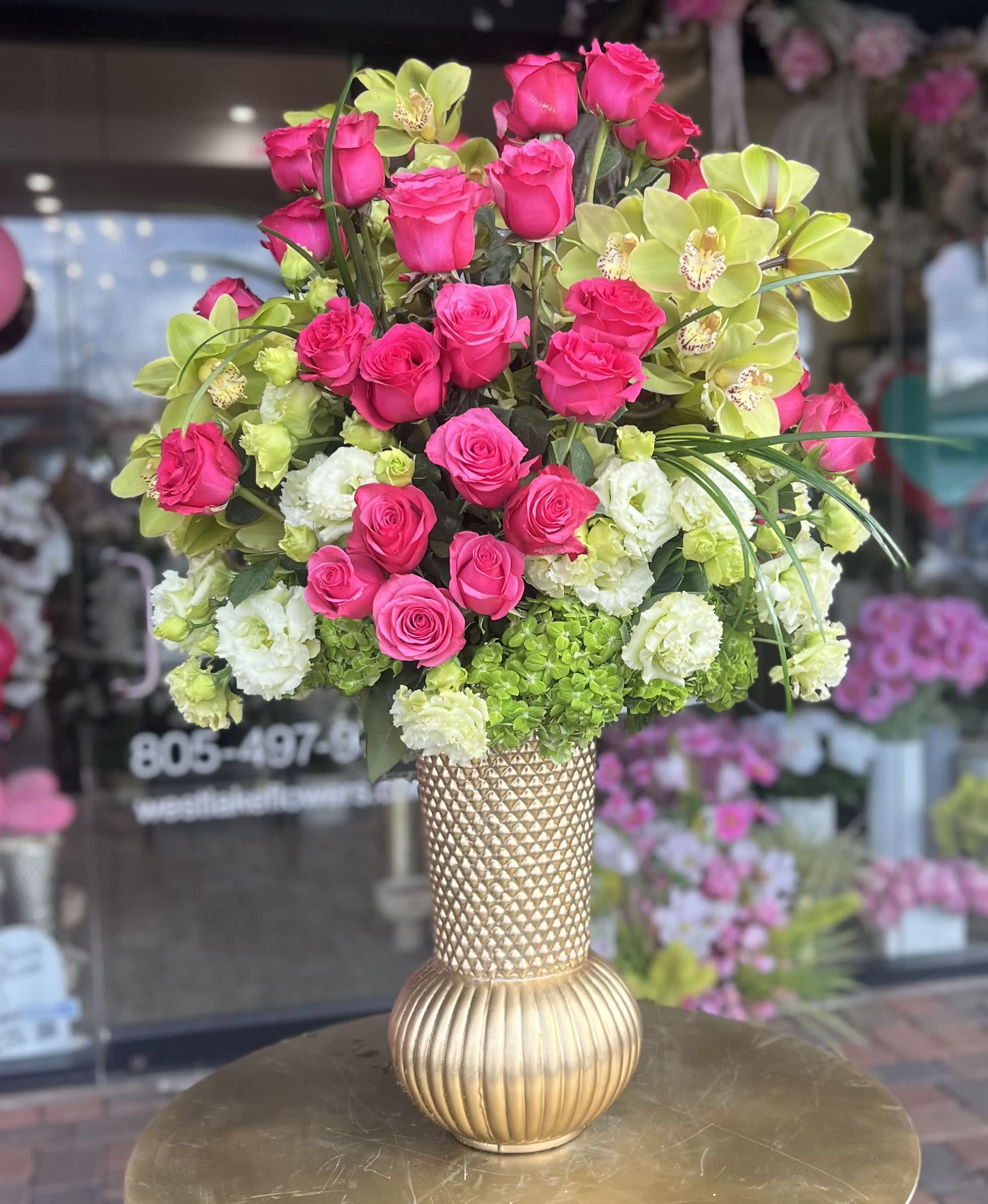 Pink roses and green orchids arranged in a gold vase