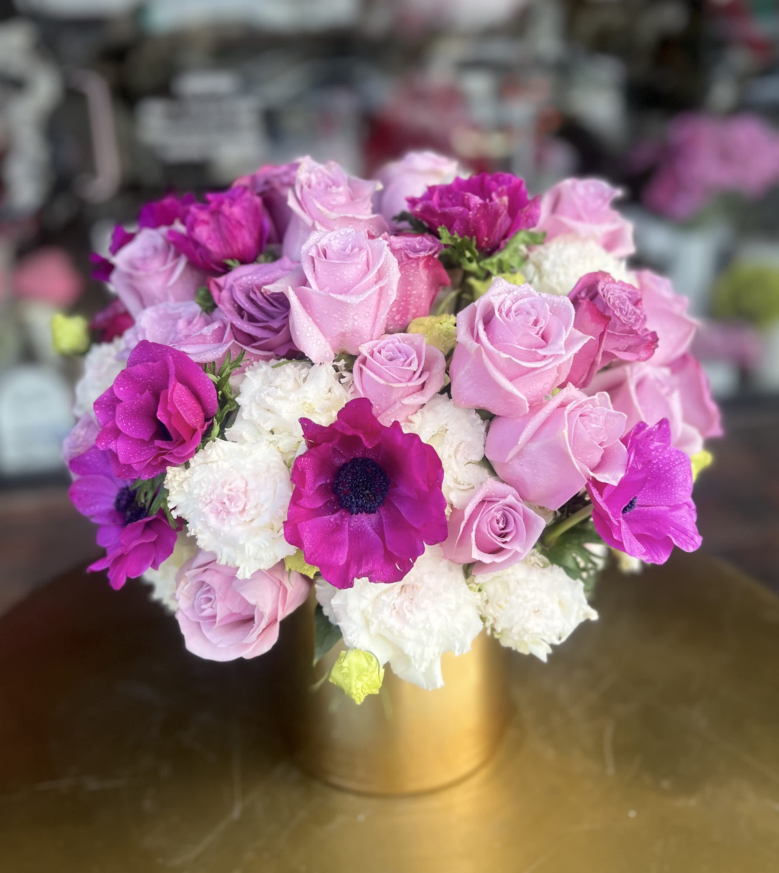 Pink and purple roses with white blooms in a gold vase