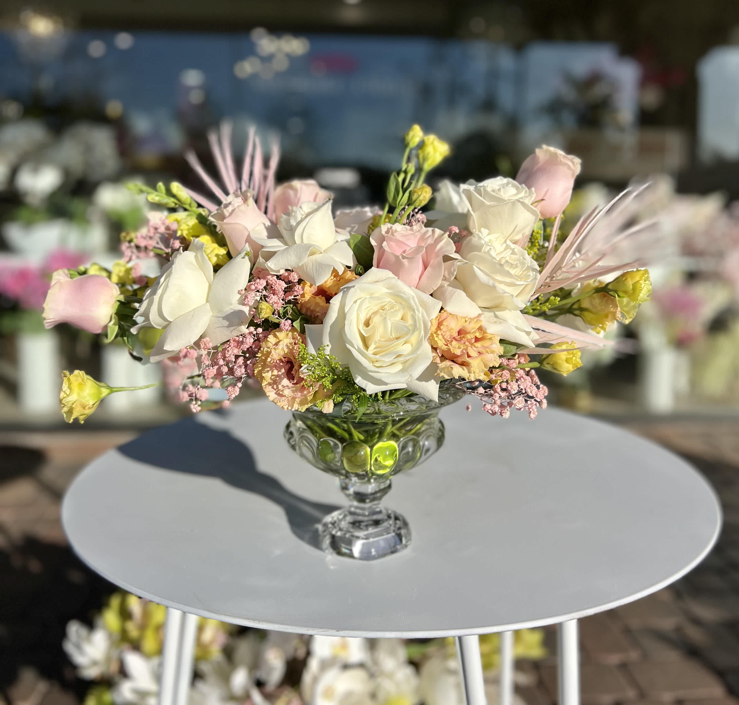 Low floral centerpiece with white and blush roses in a glass compote vase