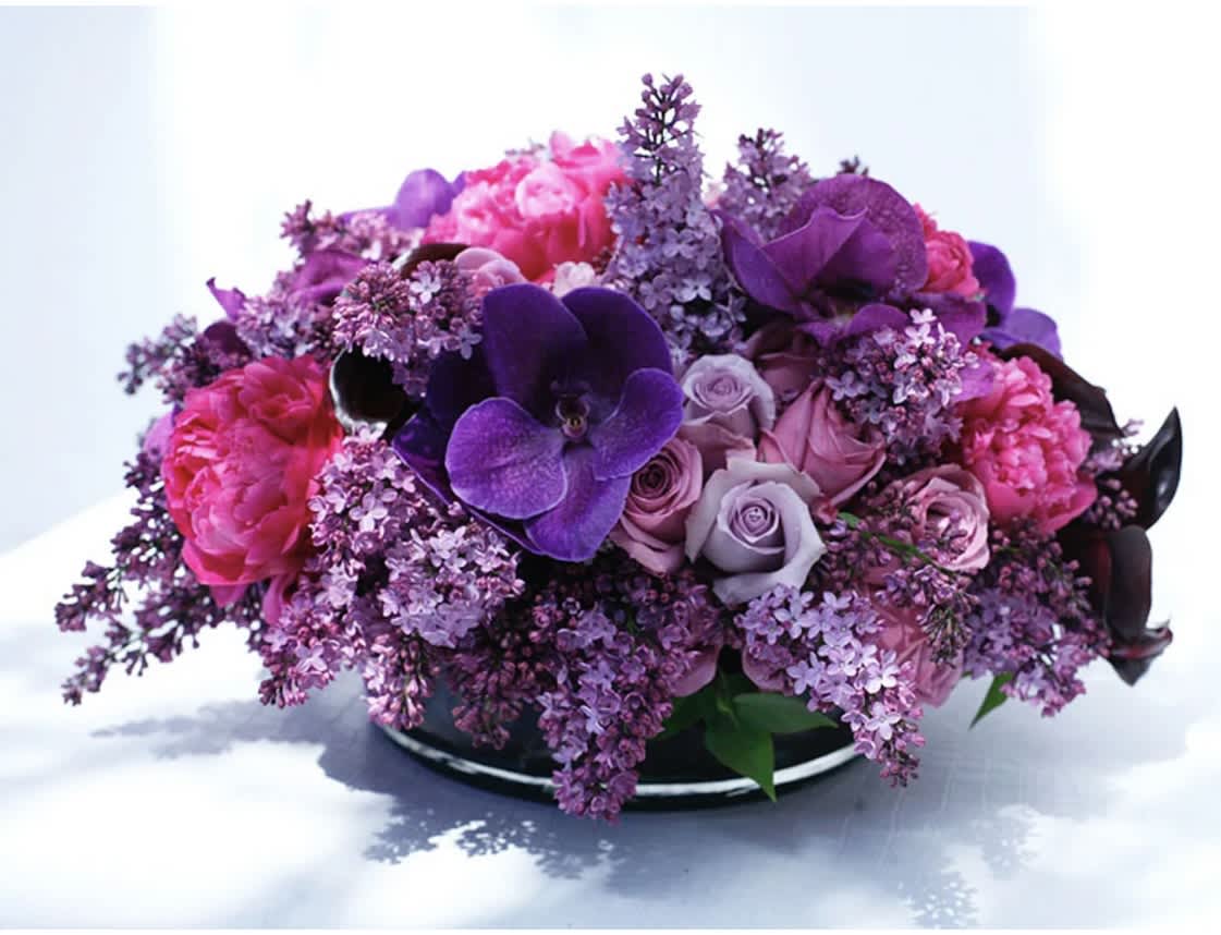 Purple and pink floral arrangement in a low black container