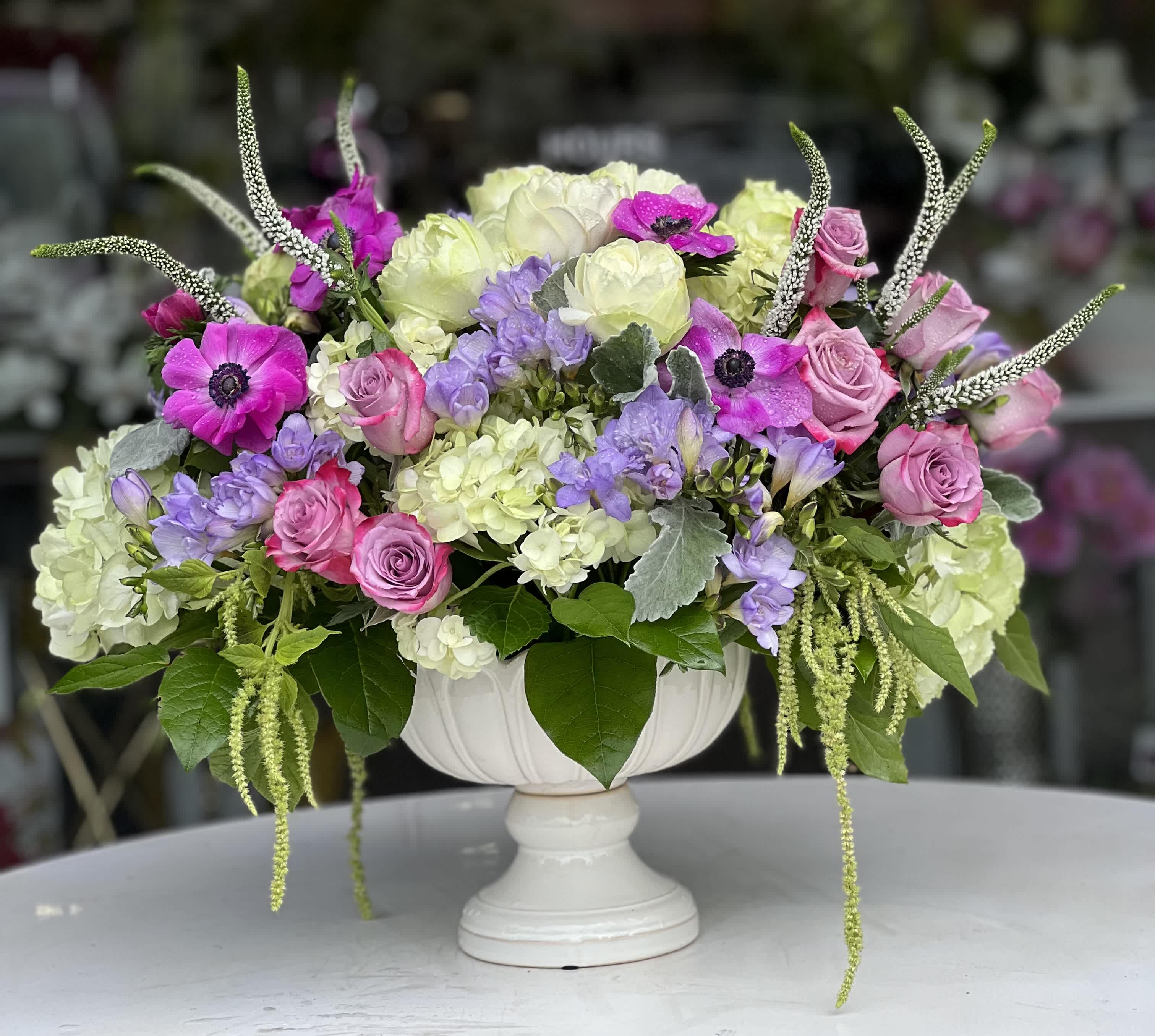 Pink and lavender flowers arranged in a white pedestal vase