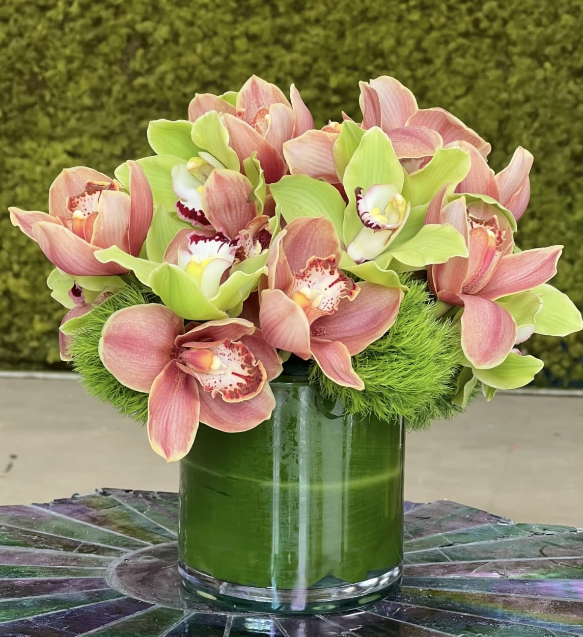 Pink and green orchids arranged in a glass vase