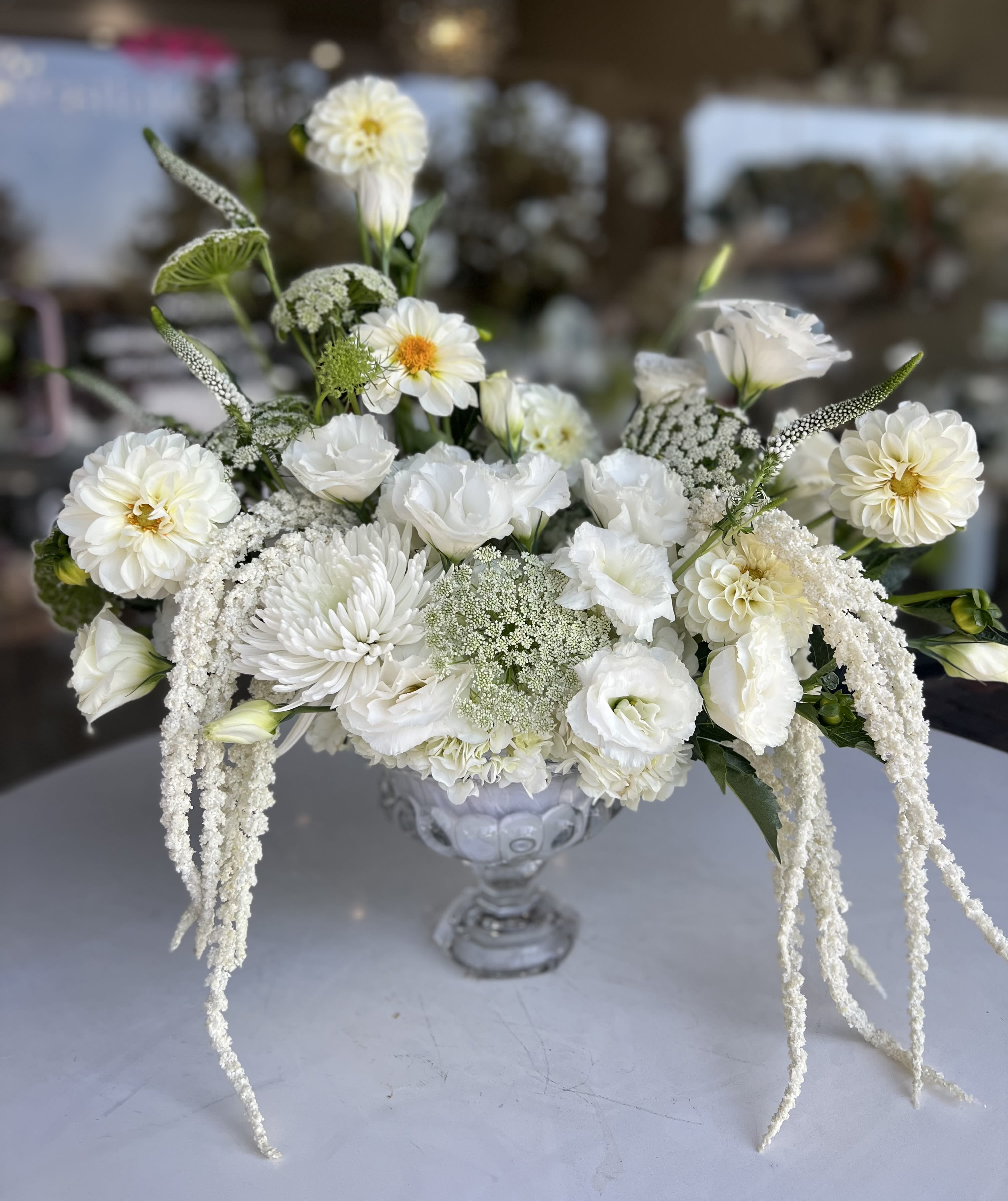 White floral arrangement in a clear glass vase with cascading blooms