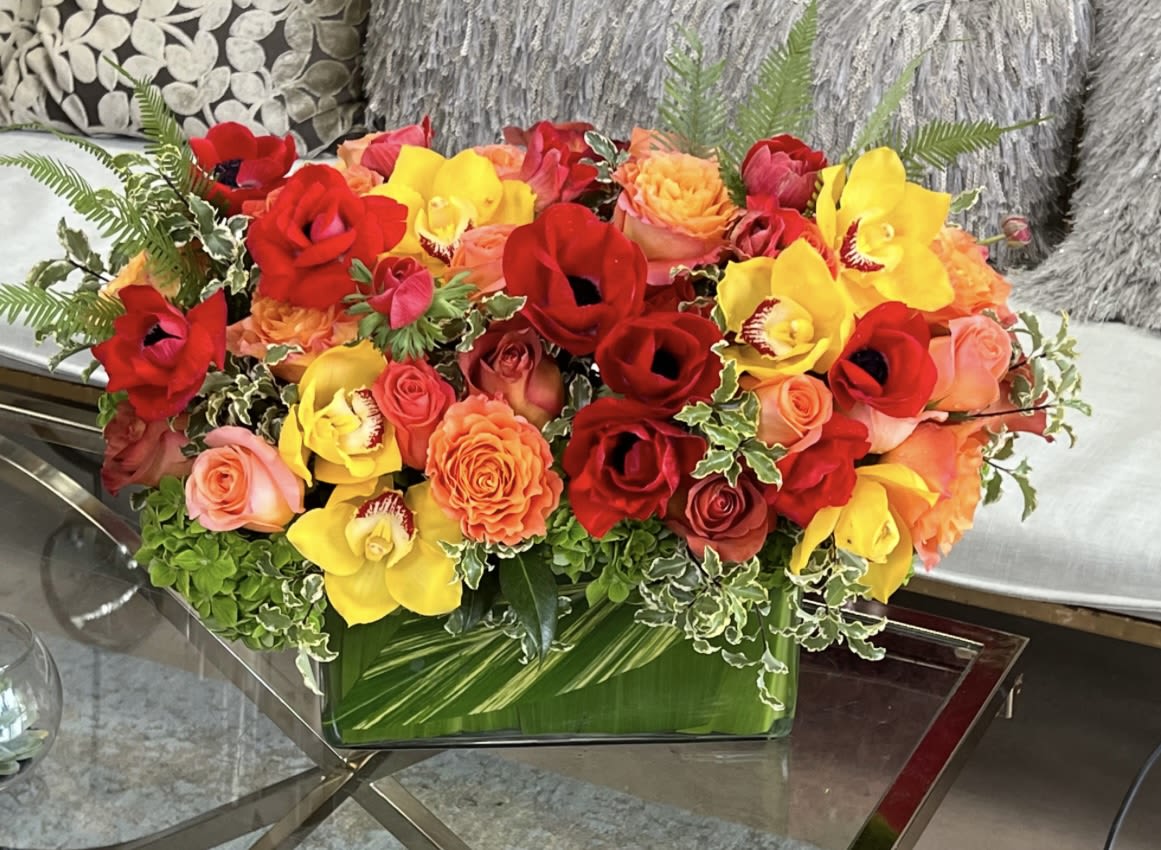 Bright mixed bouquet of red, yellow, and orange flowers in a glass vase